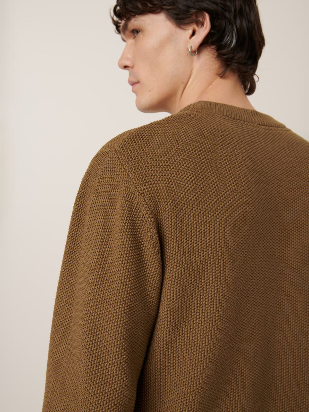 A person with short brown hair wears the Judd Crew – Dark Spice by Kowtow, a relaxed fit textured brown knit sweater, shown from the back and in profile against a plain background.