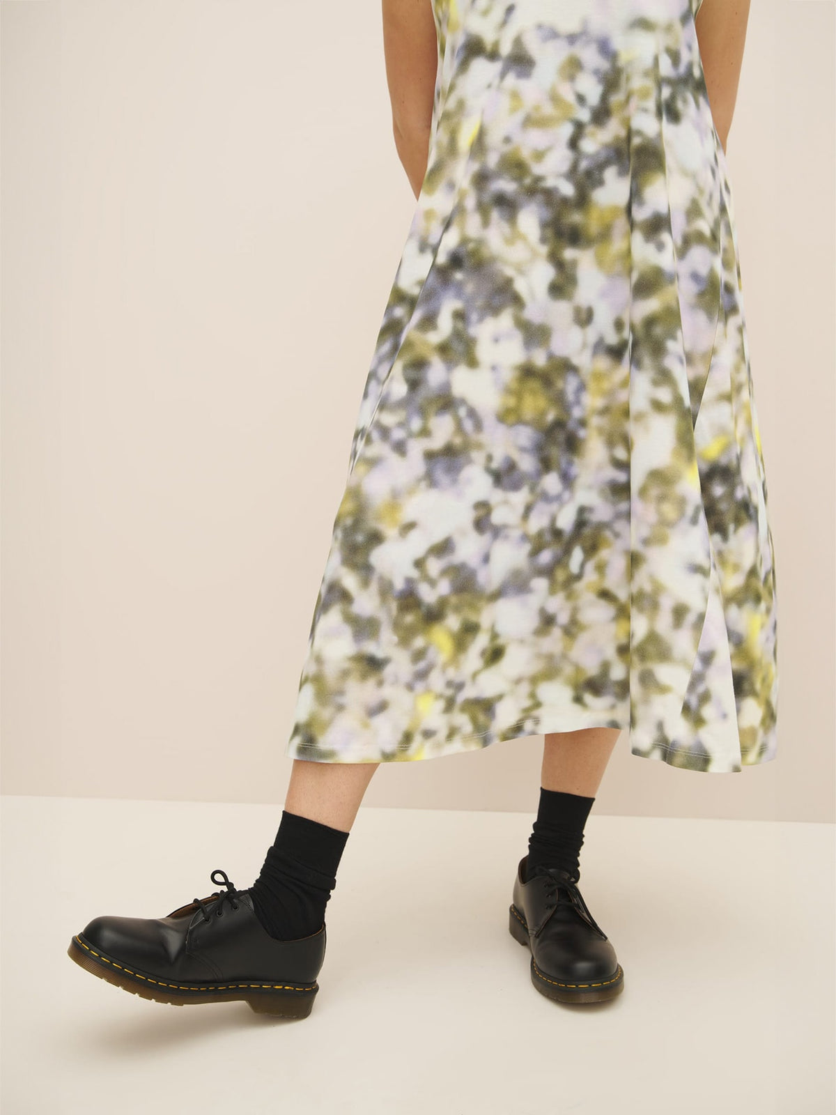 A woman wearing a Komorebi Dress by Kowtow made of organic cotton and black shoes.