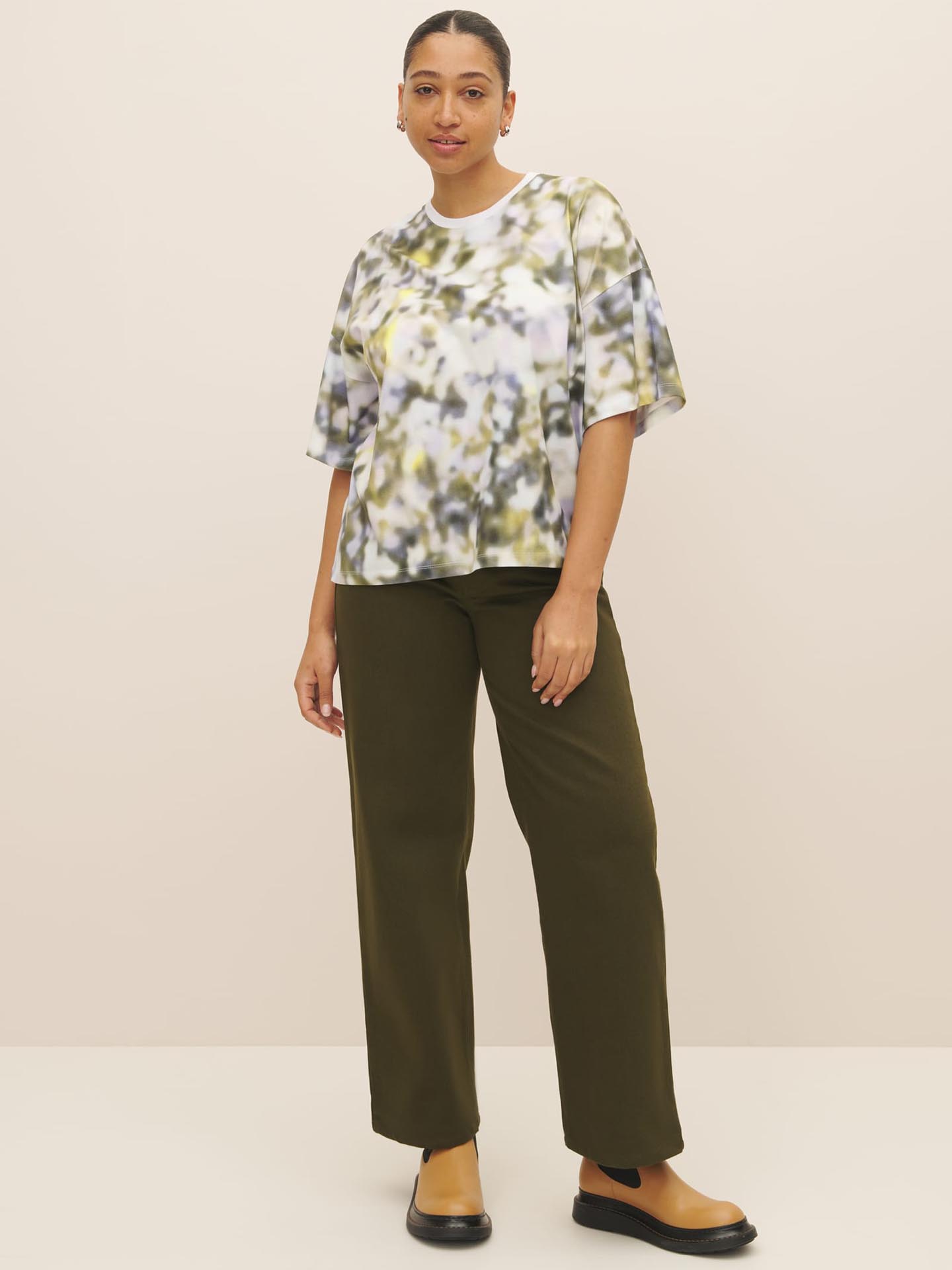 An environmentally conscious woman wearing a Kowtow Komorebi Print Tee made from Fairtrade organic cotton paired with comfortable olive wide leg pants.