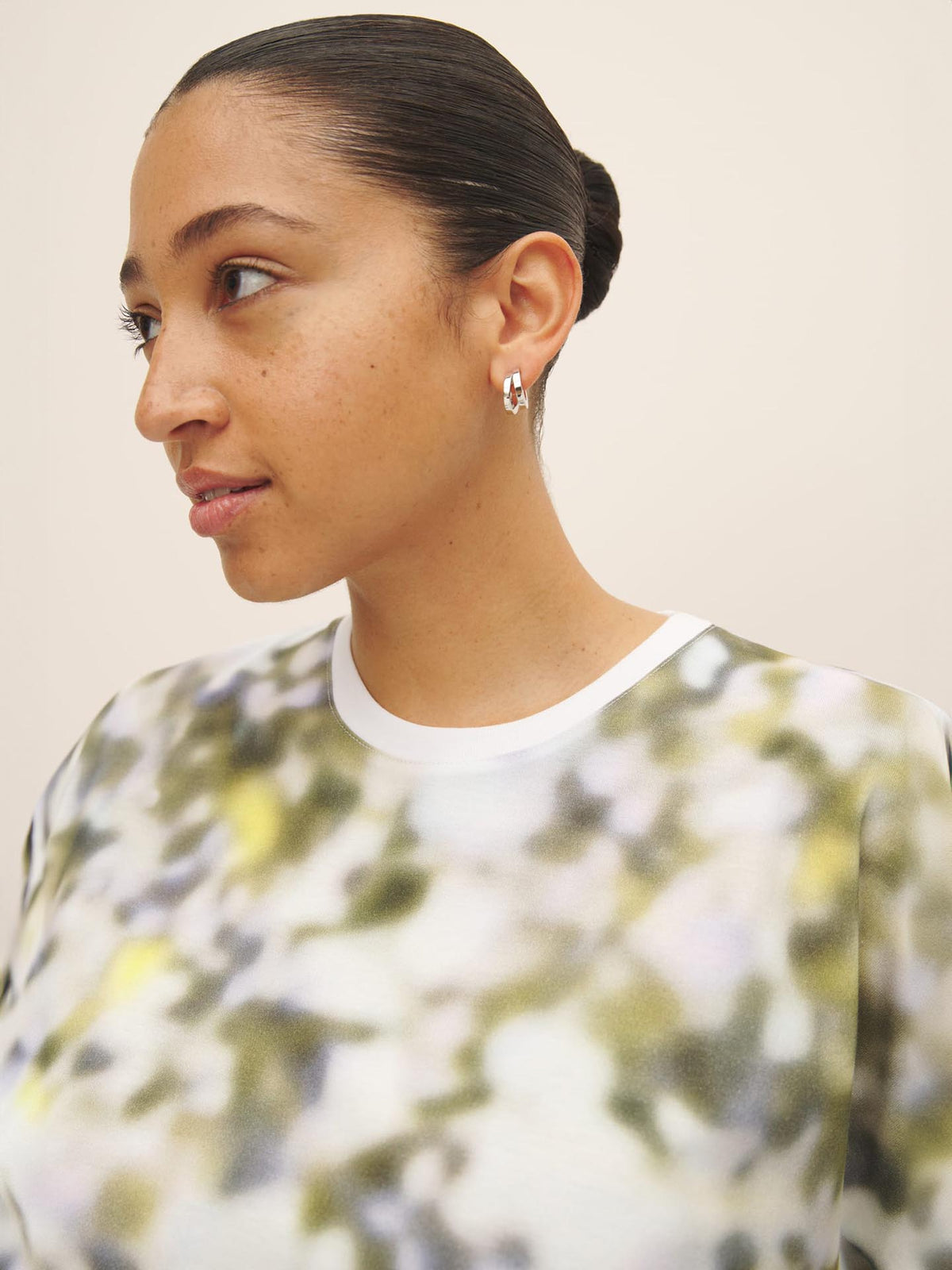 A woman wearing an oversized green and white floral print Komorebi Print Tee made from Fairtrade organic cotton by Kowtow.