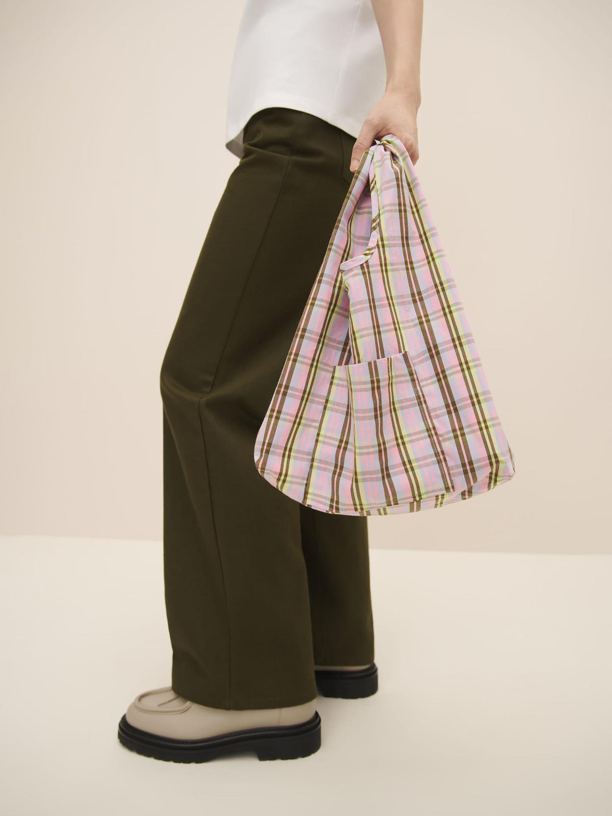 Person standing with a Kowtow Mini Market Bag – Pink Tartan on a neutral background.