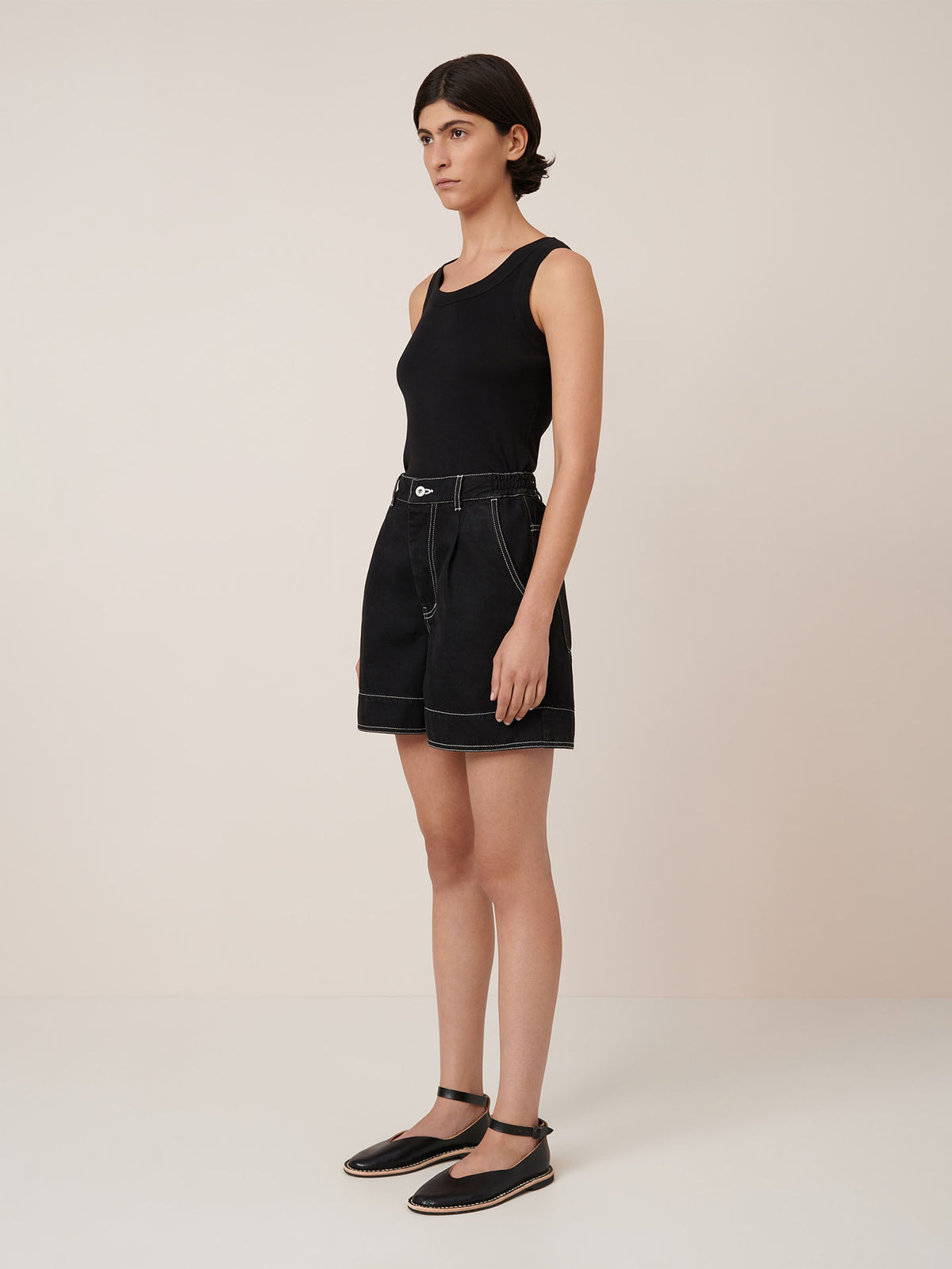 A person stands against a plain background wearing Kowtow&#39;s Outline Shorts in black.