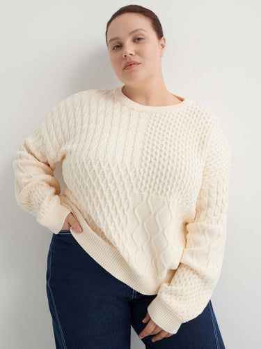 A person wears the Patchwork Jumper – Chalk, a cream-colored textured knit with a boxy silhouette, paired with dark blue jeans, standing against a plain white background.