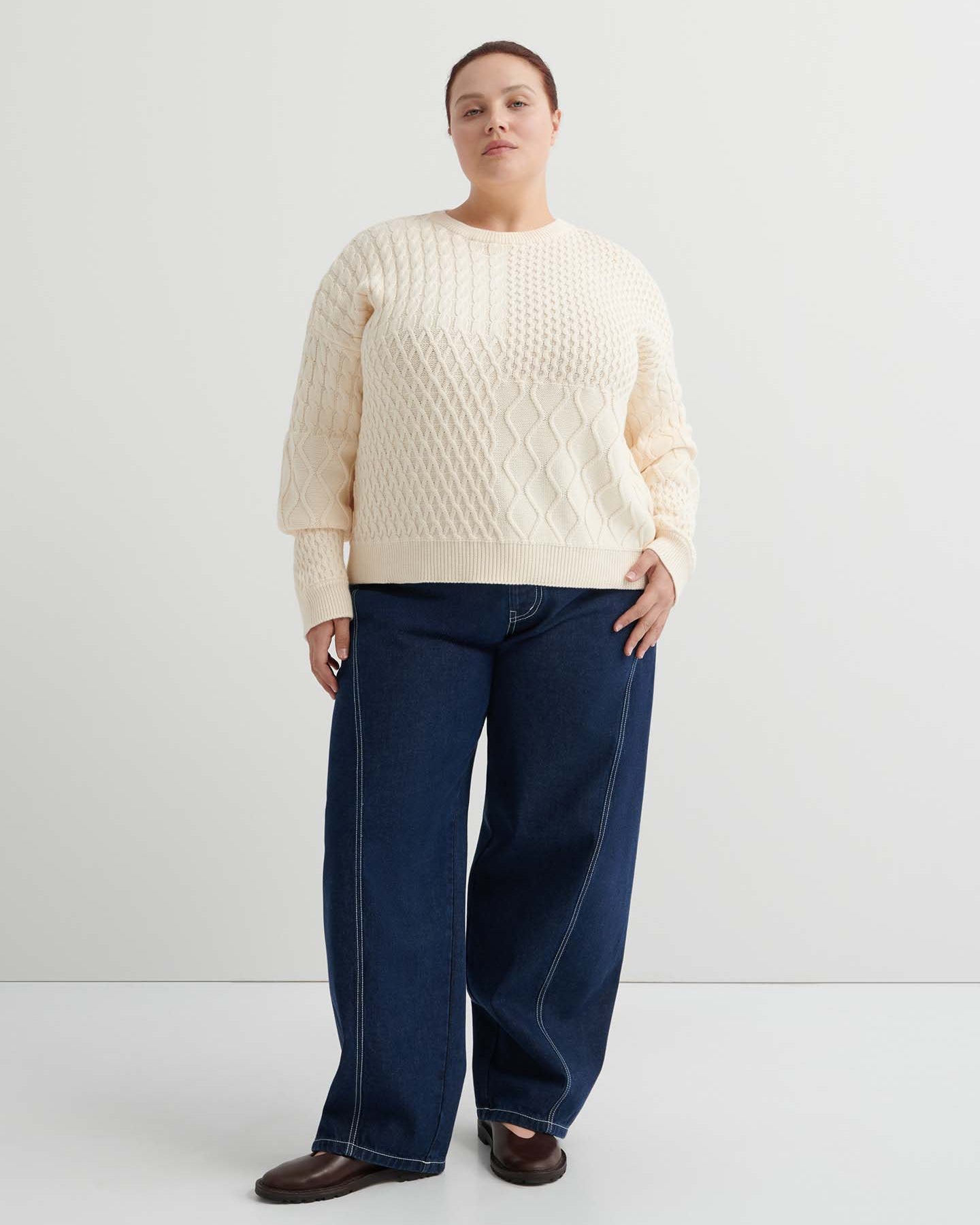 A person wears the Patchwork Jumper – Chalk, a cream-colored textured knit with a boxy silhouette, paired with dark blue jeans, standing against a plain white background.
