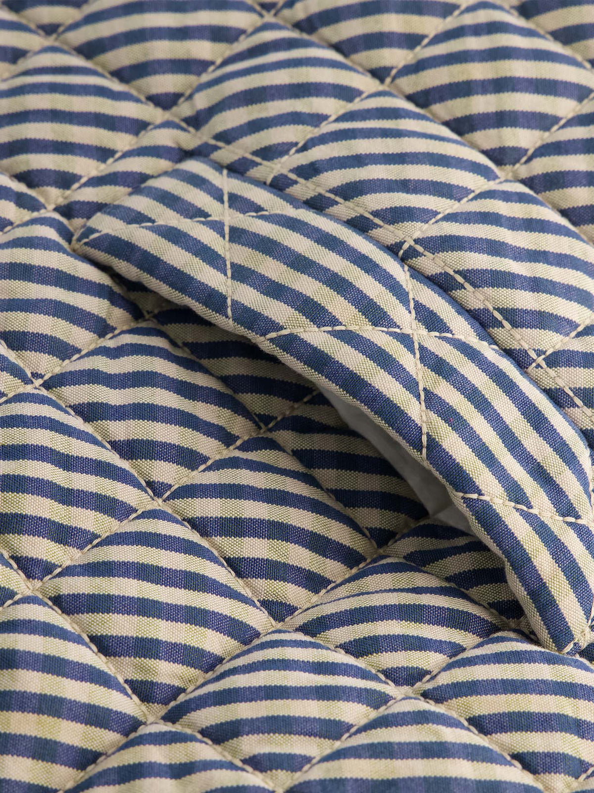 Close-up of quilted fabric in blue and beige check, featuring a sewn-in flap pocket—perfect for layering with the relaxed fit of the Quilter Vest – Landscape check.