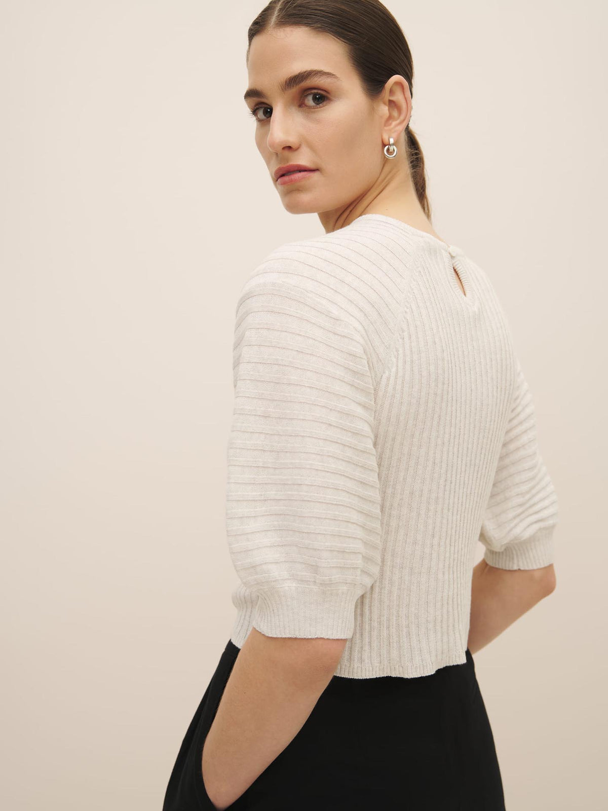 Woman in a Kowtow Quinn Top – Light Marle organic cotton beige striped sweater looking over her shoulder.