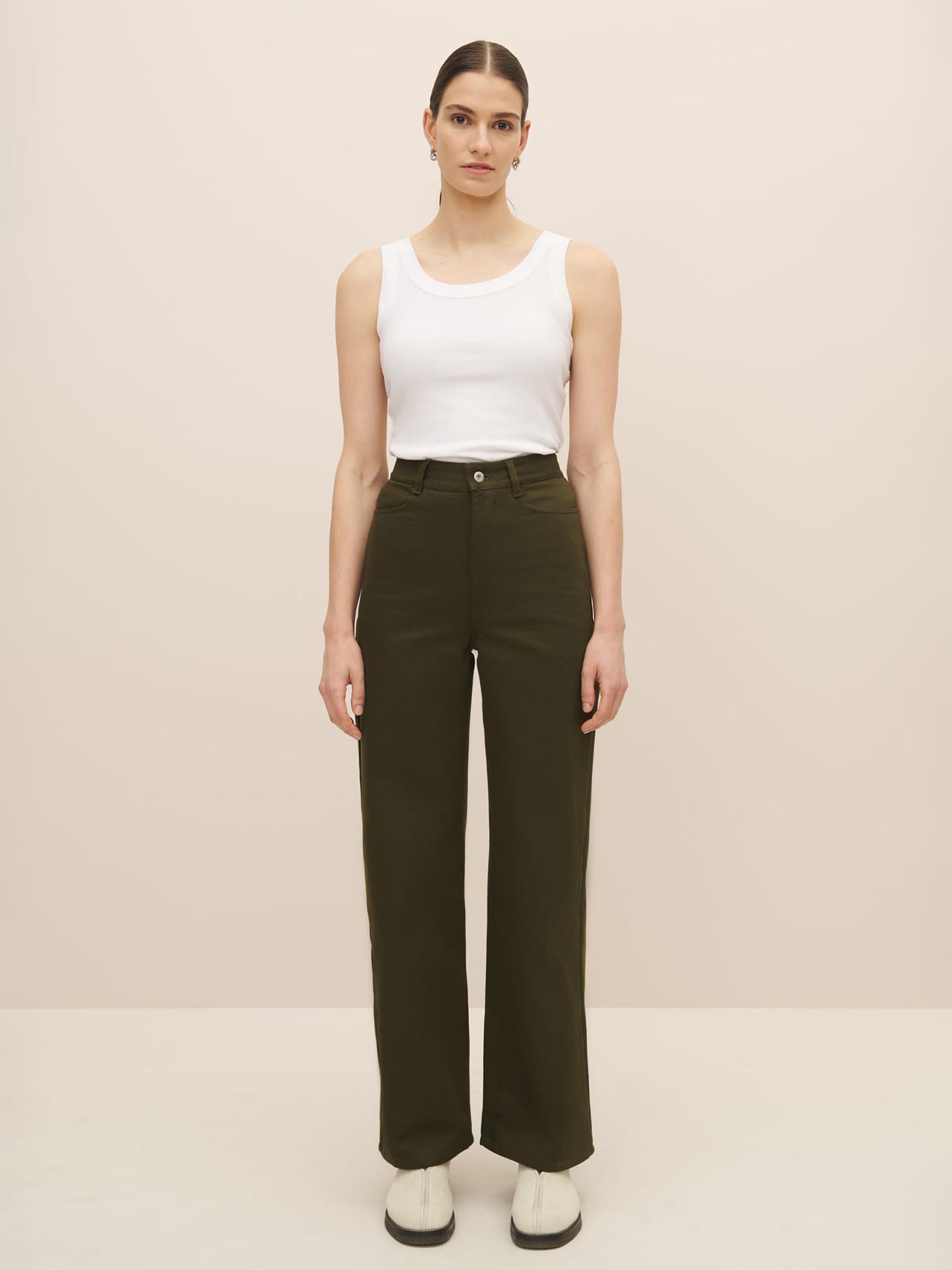 The model is wearing a white tank top and olive green fairtrade organic cotton Straight Leg Jeans – Khaki Denim pants by Kowtow.