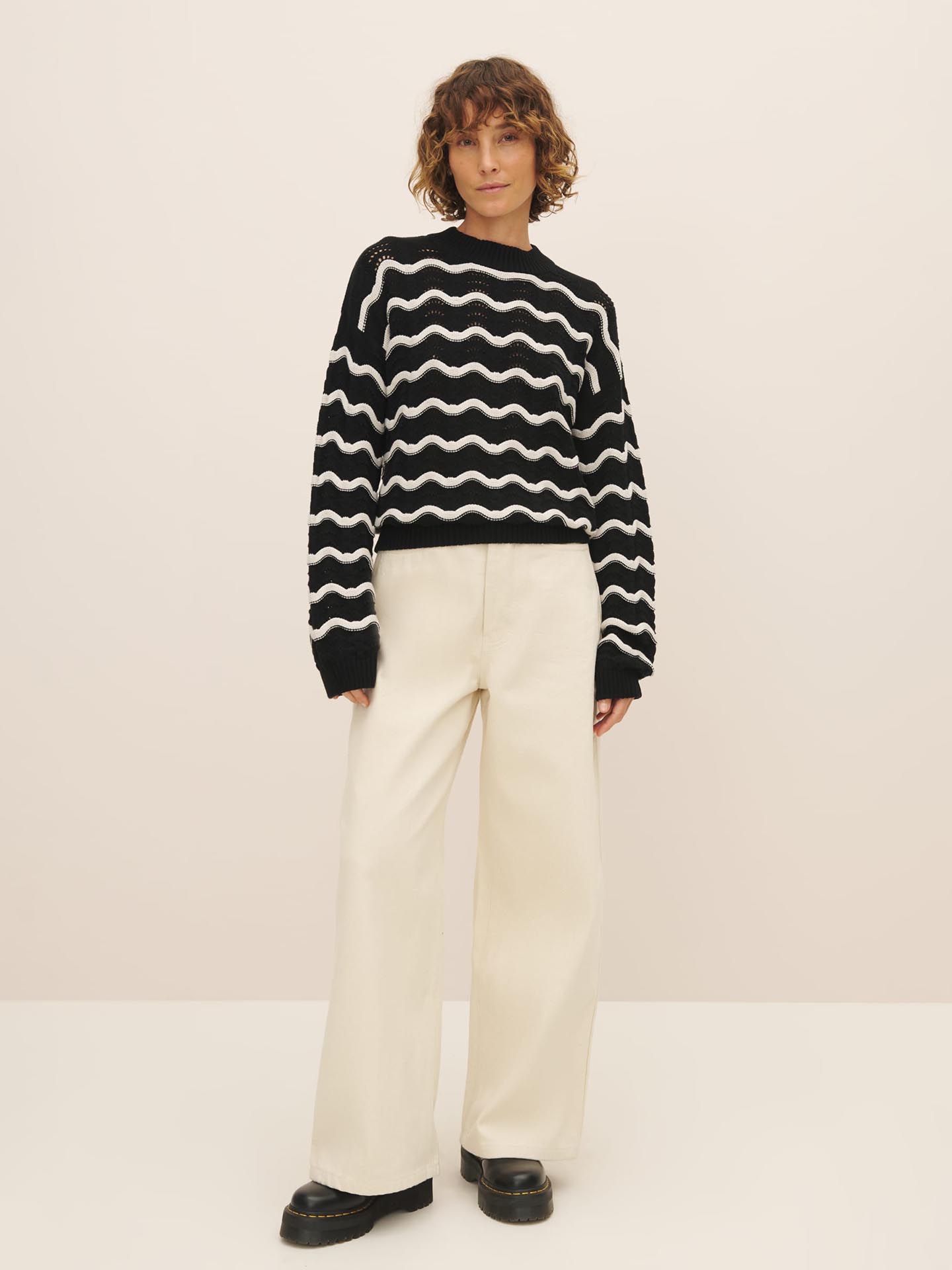 Woman posing in a Tide Jumper made from Fairtrade organic cotton by Kowtow, and white trousers.