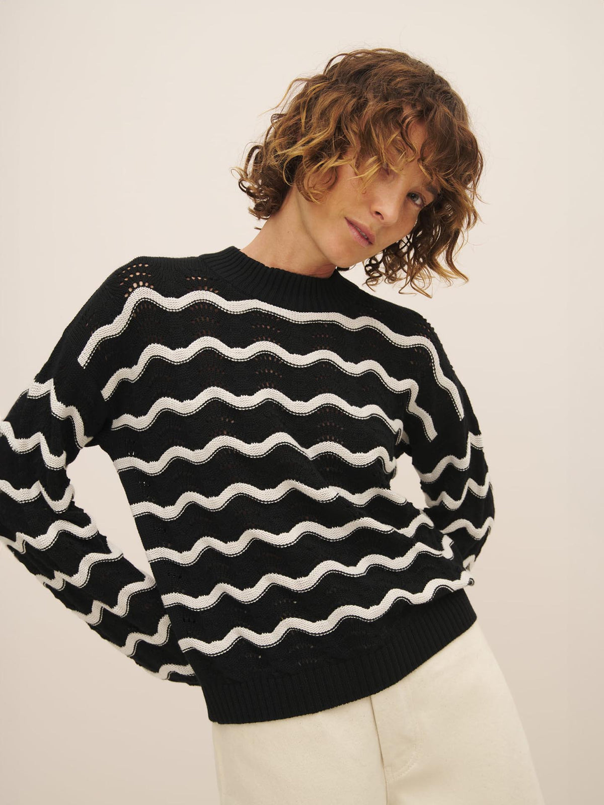 Person with curly hair posing in a black and white striped Tide Jumper made of Fairtrade organic cotton by Kowtow.