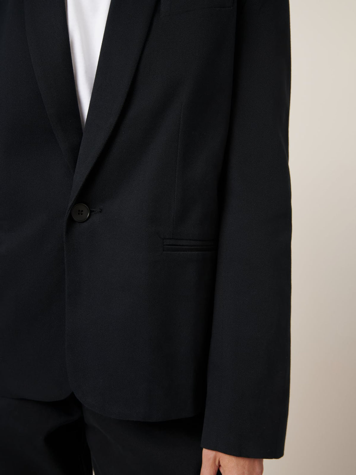 A person in a Kowtow Tux Jacket – Black, along with matching pants, is standing against a plain background.