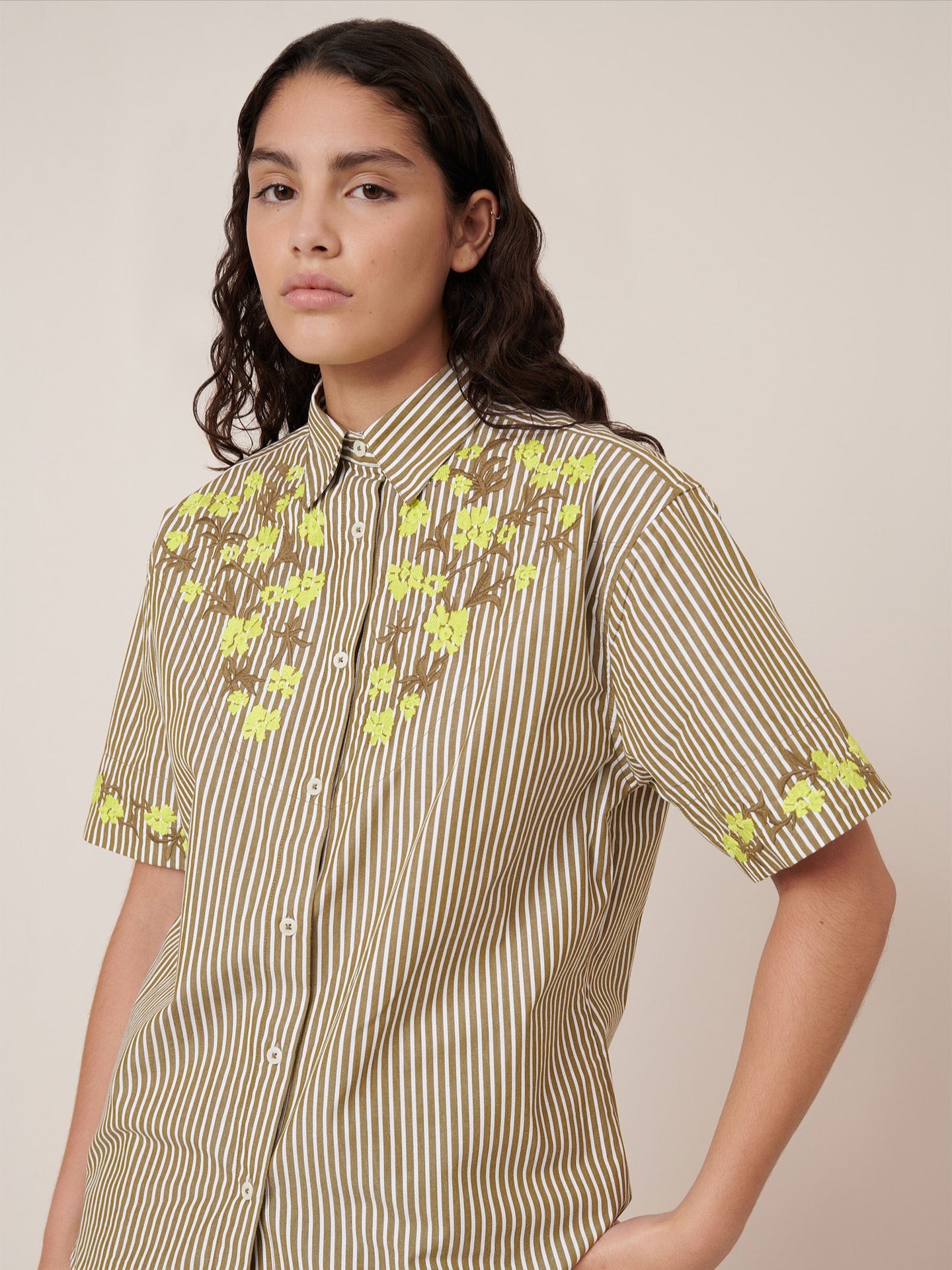 Woman wearing a patterned shirt with short sleeves on a plain background