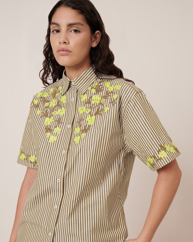 Woman wearing a patterned shirt with short sleeves on a plain background