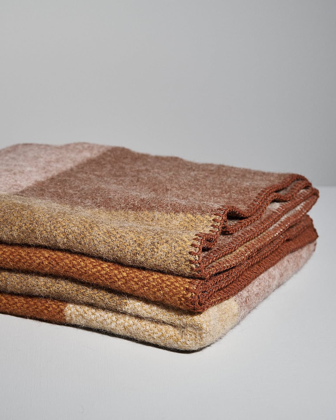 Klippan's Block Wool Throw – Rust, featuring a color-block design in shades of brown, beige, and cream, made from eco-friendly wool.