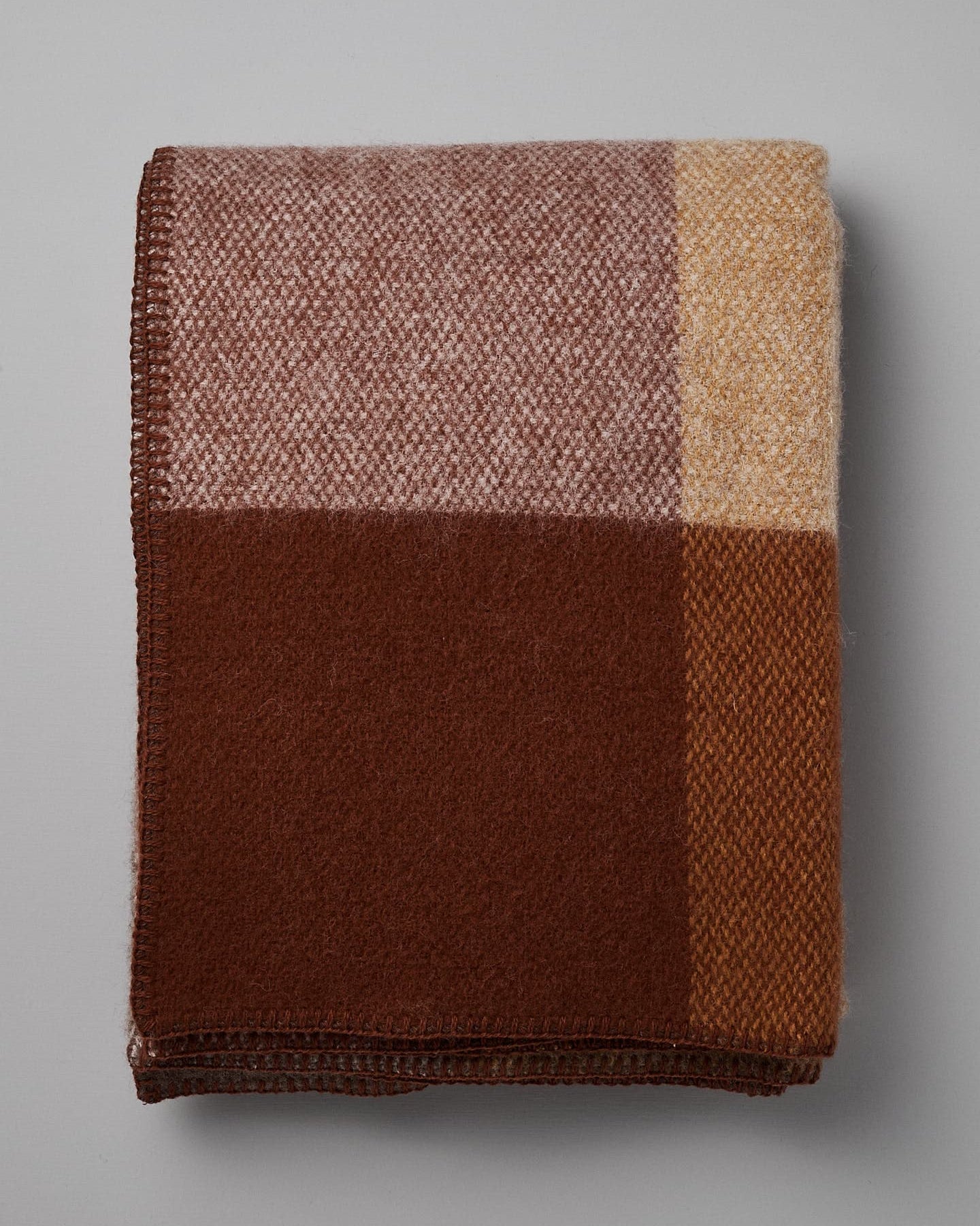 Klippan's Block Wool Throw – Rust, featuring a color-block design in shades of brown, beige, and cream, made from eco-friendly wool.