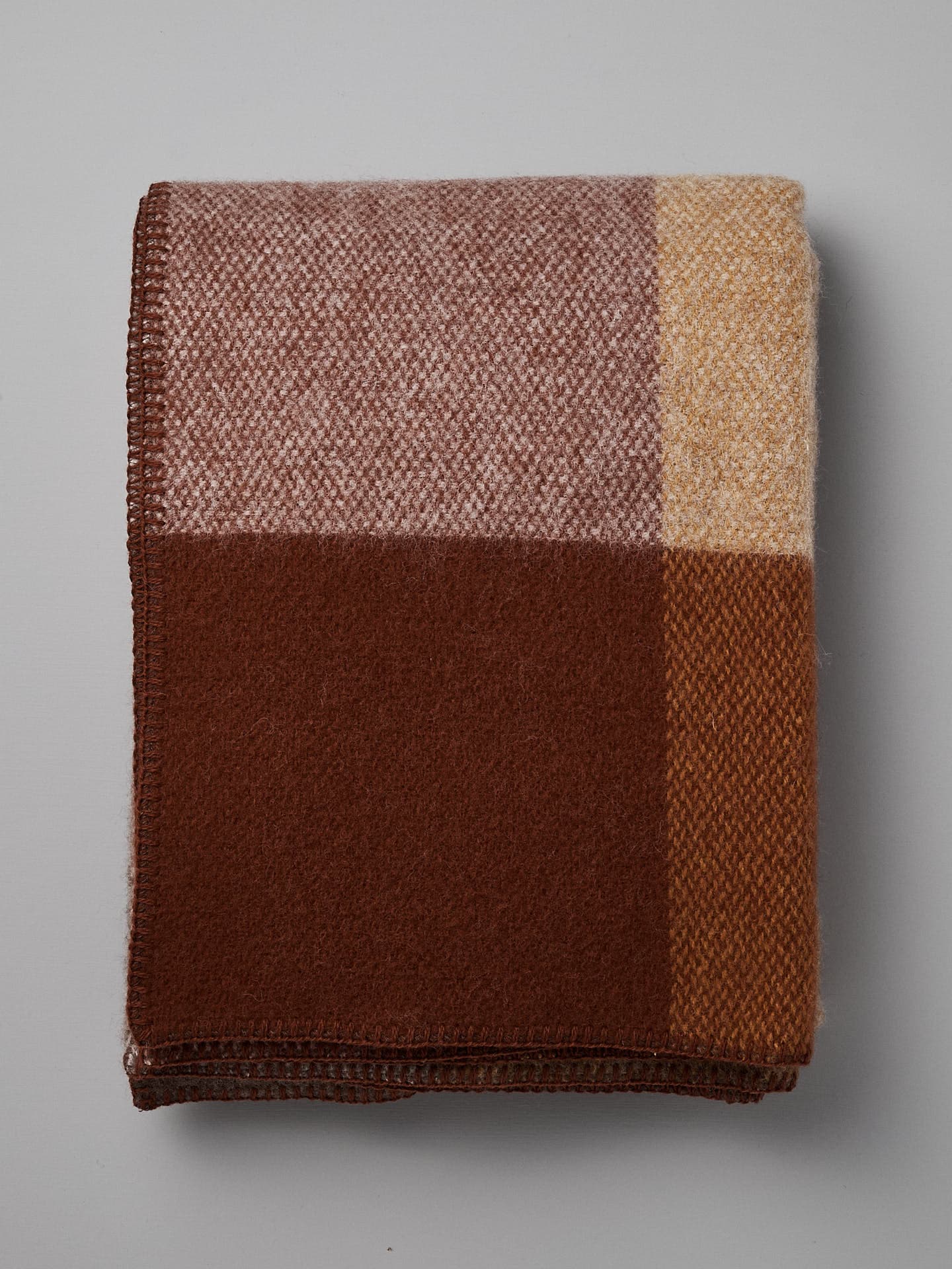 Klippan's Block Wool Throw – Rust, featuring a color-block design in shades of brown, beige, and cream, made from eco-friendly wool.