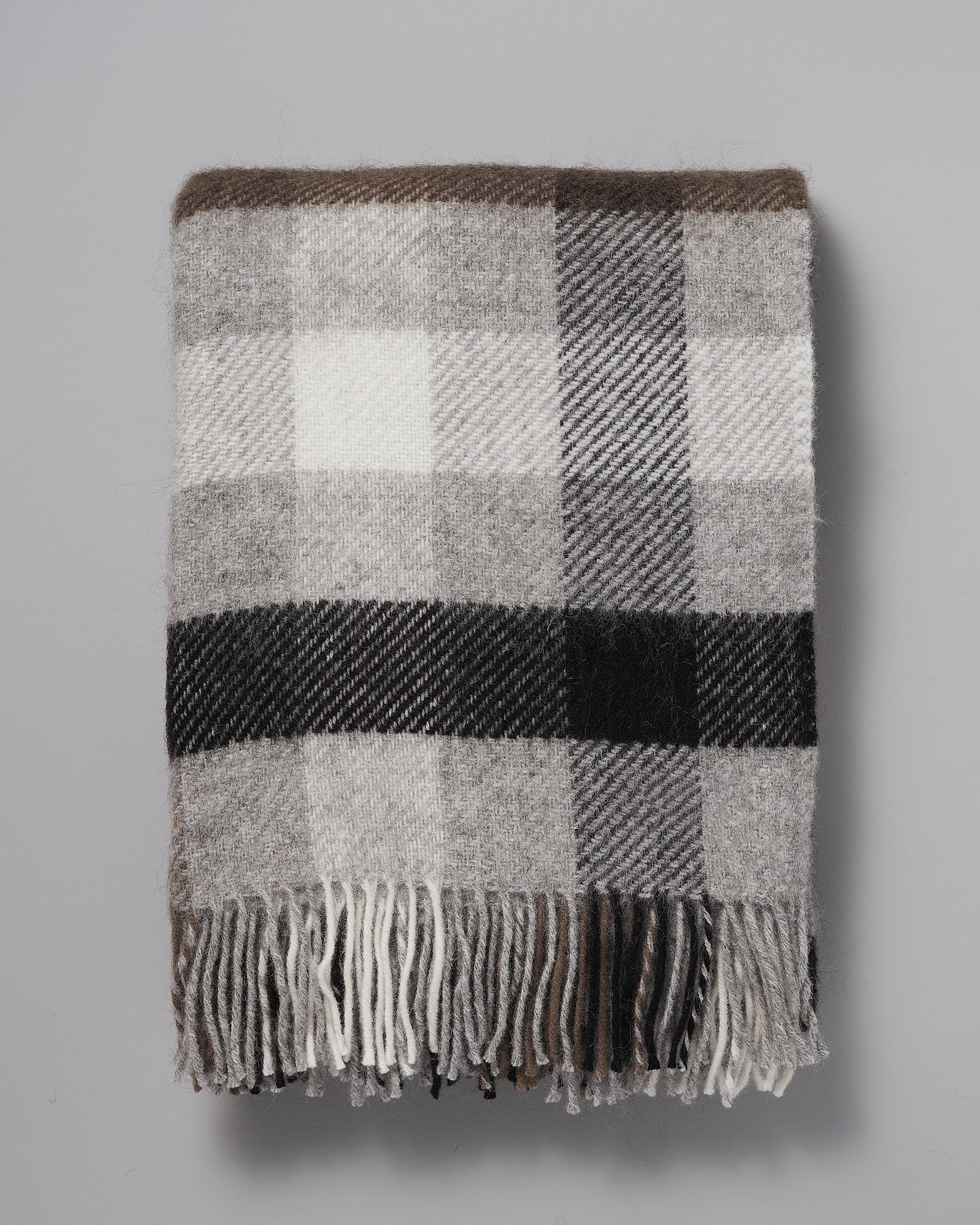 A Klippan Gotland Wool Throw – Multi Grey on a grey background.