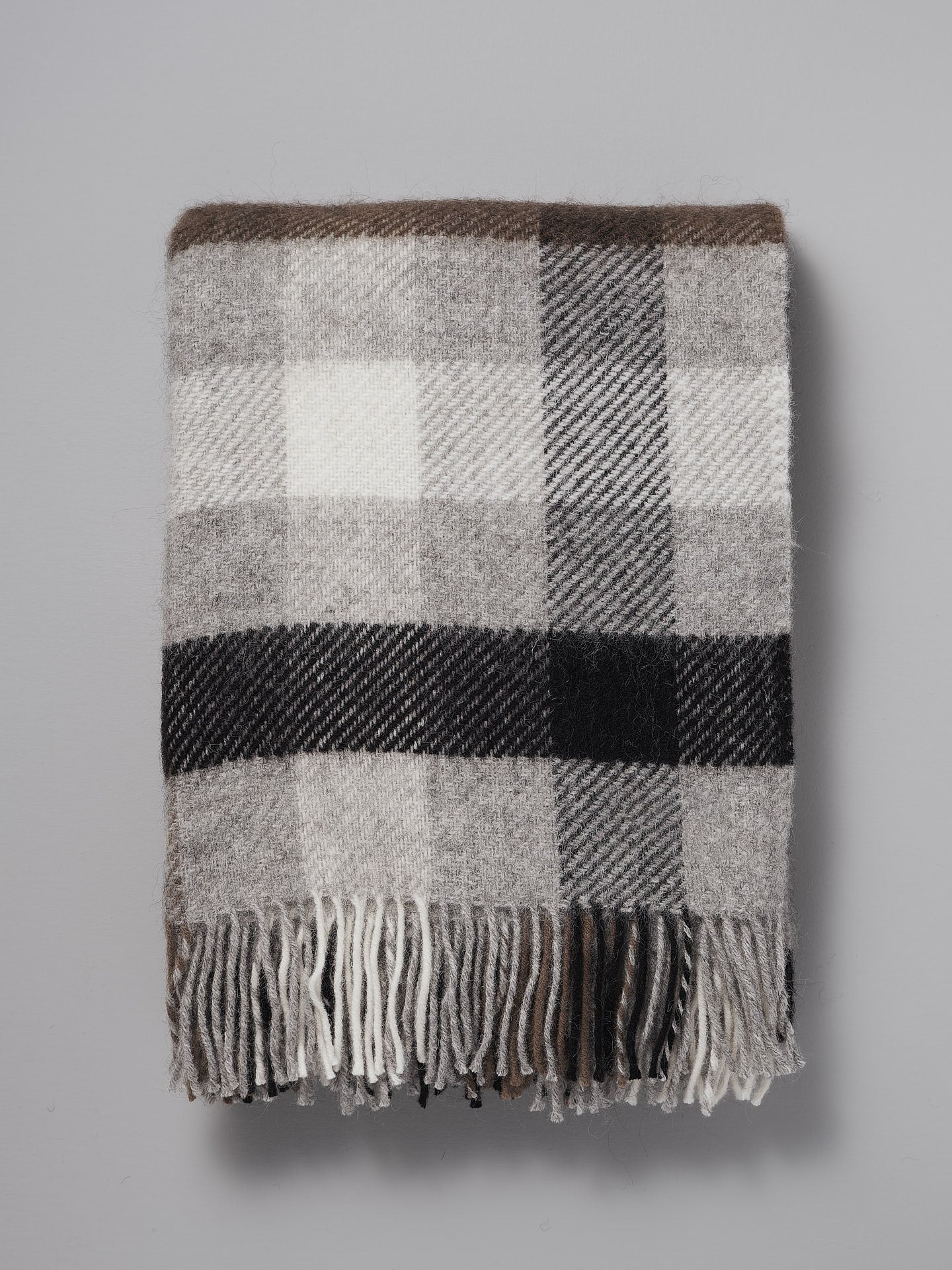 A Klippan Gotland Wool Throw – Multi Grey on a grey background.