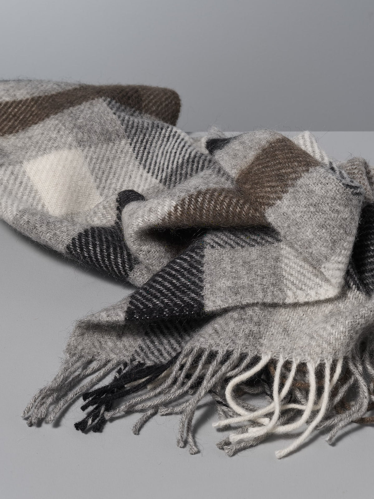 A Klippan Gotland Wool Throw – Multi Grey on a white surface.