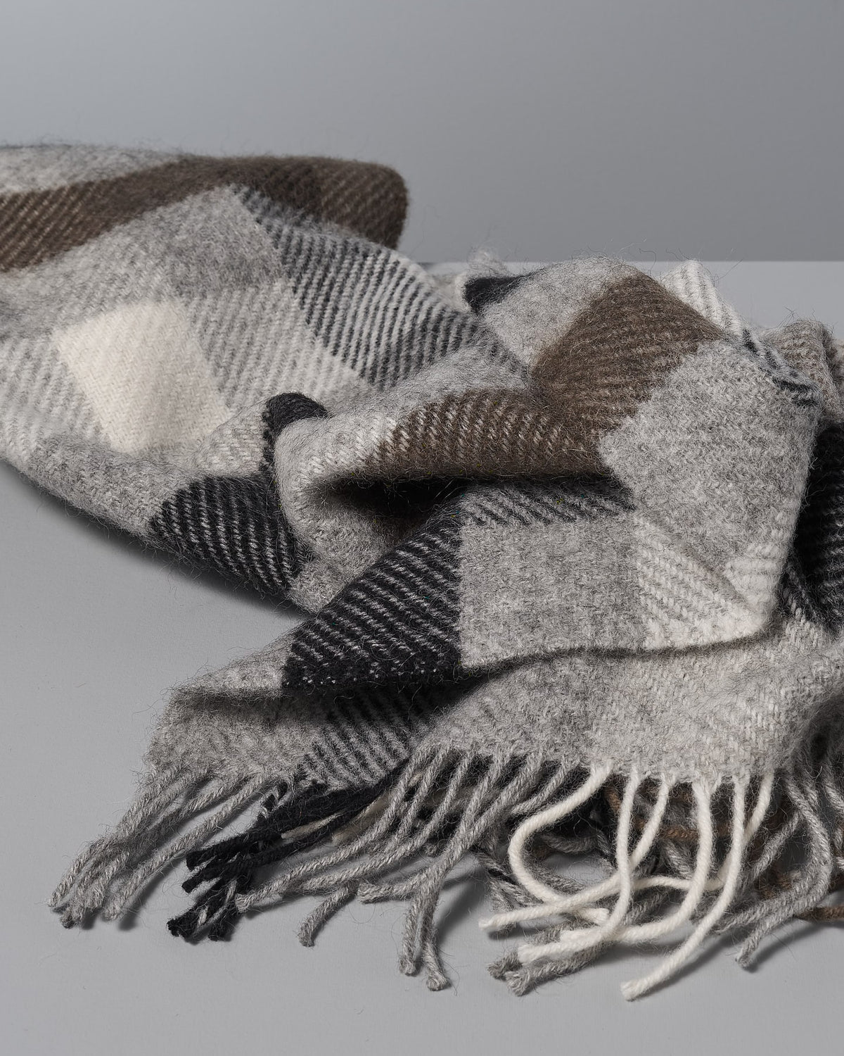 A Klippan Gotland Wool Throw – Multi Grey on a white surface.