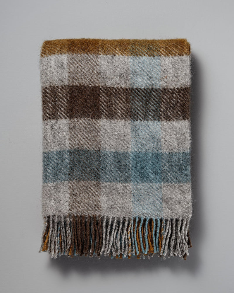 A Gotland Wool Throw – Multi Turquoise with fringes on a white background.
