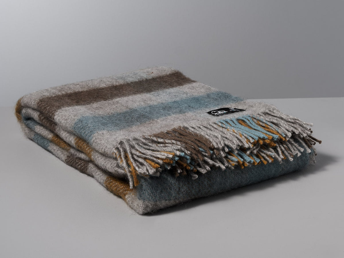A Gotland Wool Throw - Multi Turquoise by Klippan on a white surface.