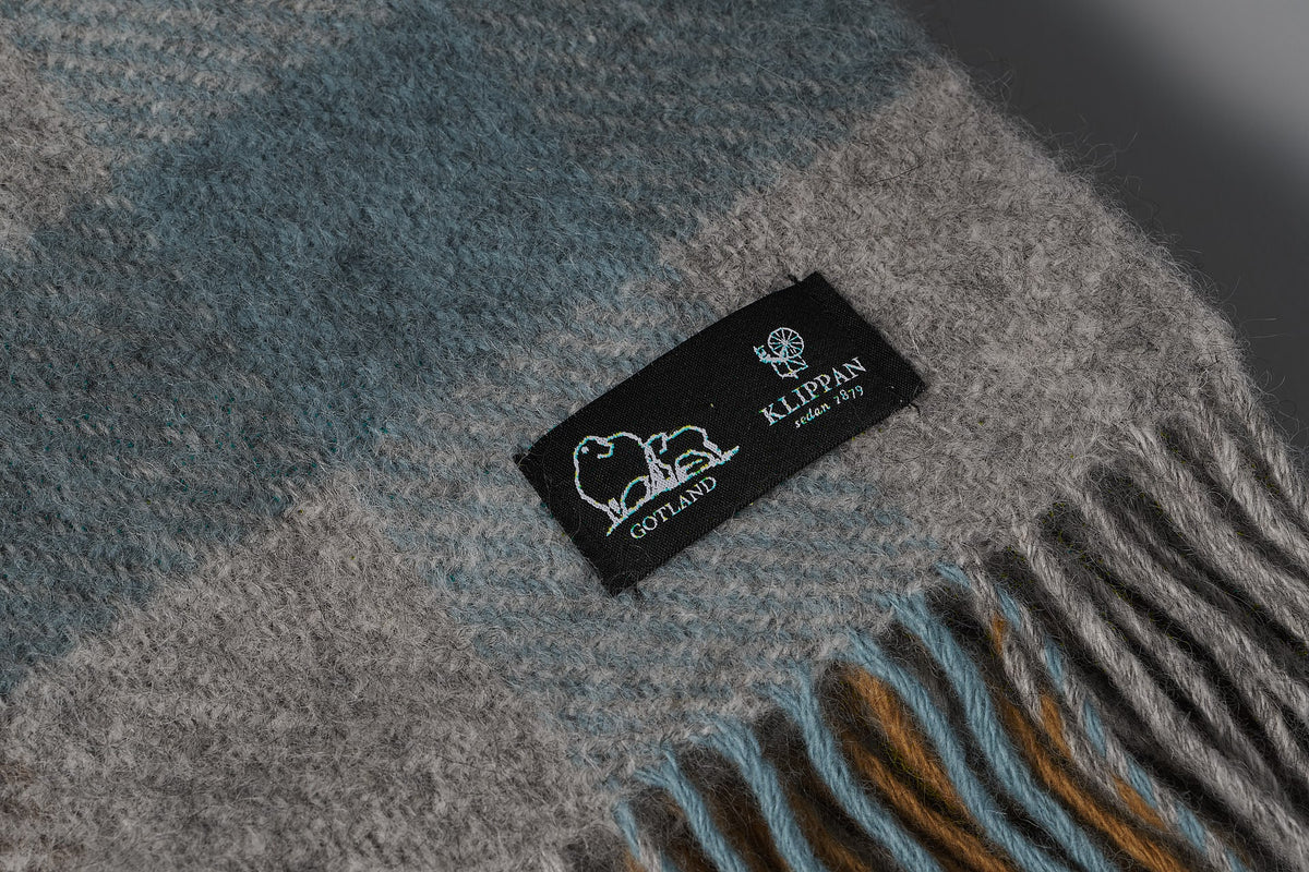 A Klippan Gotland Wool Throw - Multi Turquoise with a label on it.