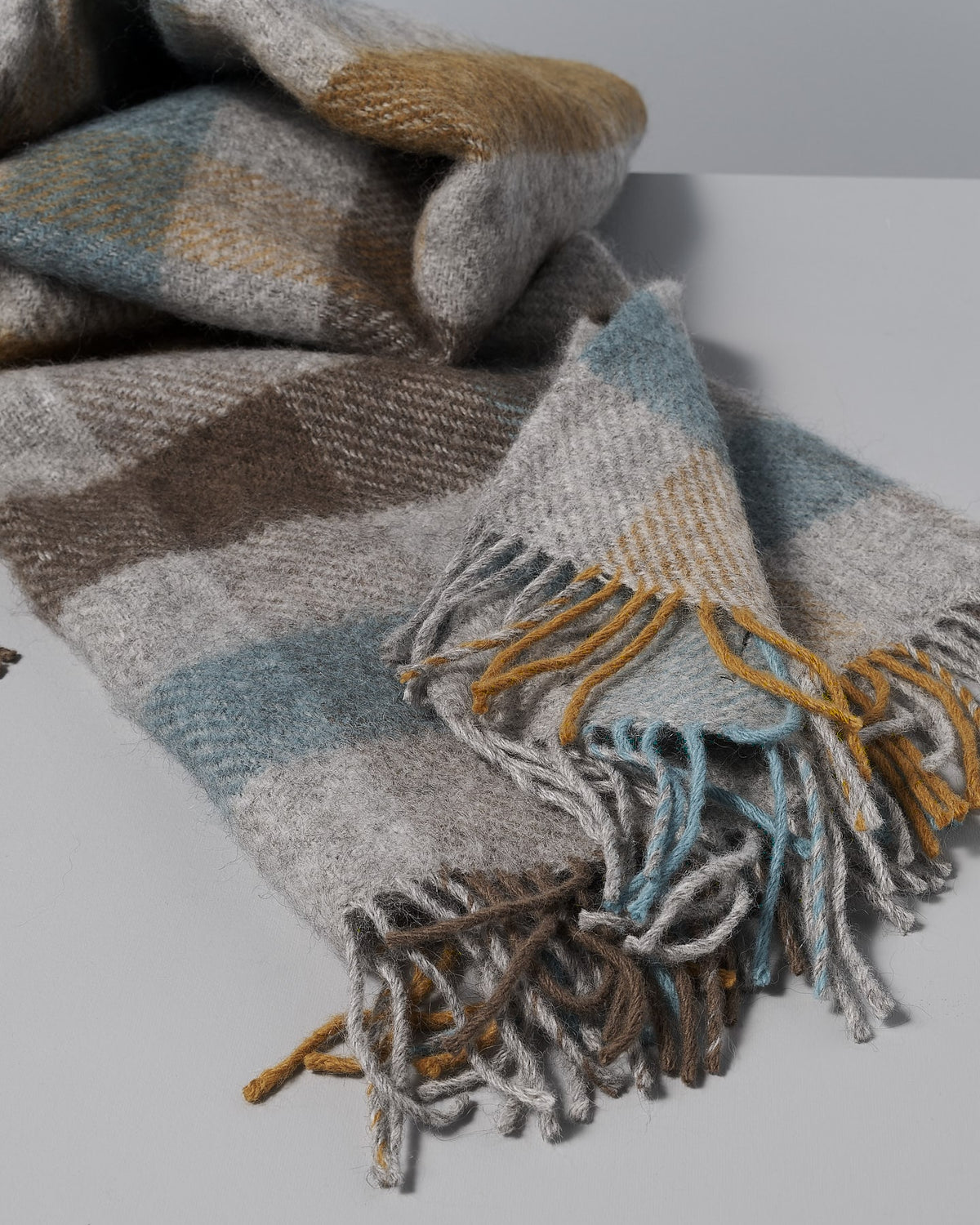 A Klippan Gotland Wool Throw – Multi Turquoise blanket with fringes.