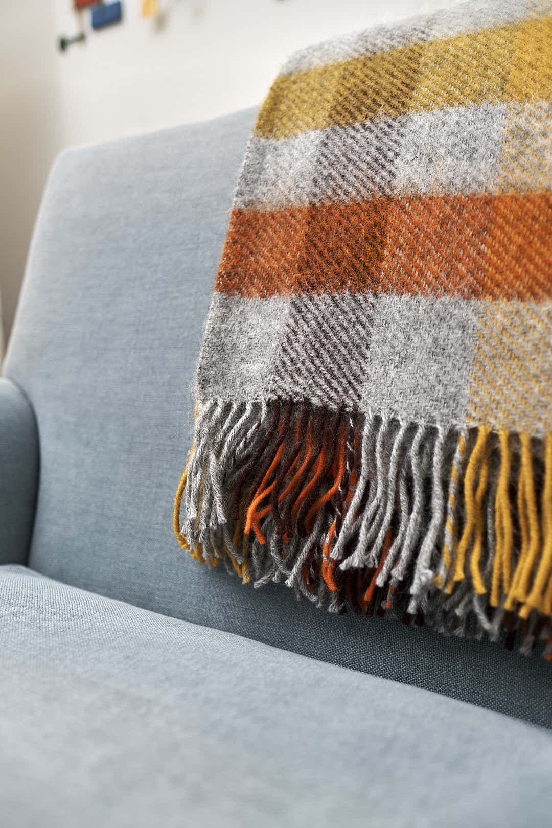 A Klippan Gotland Wool Throw – Multi Yellow on a couch in a living room.