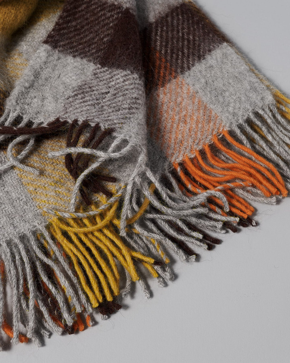 A Klippan Gotland Wool Throw – Multi Yellow with fringes on a white background.