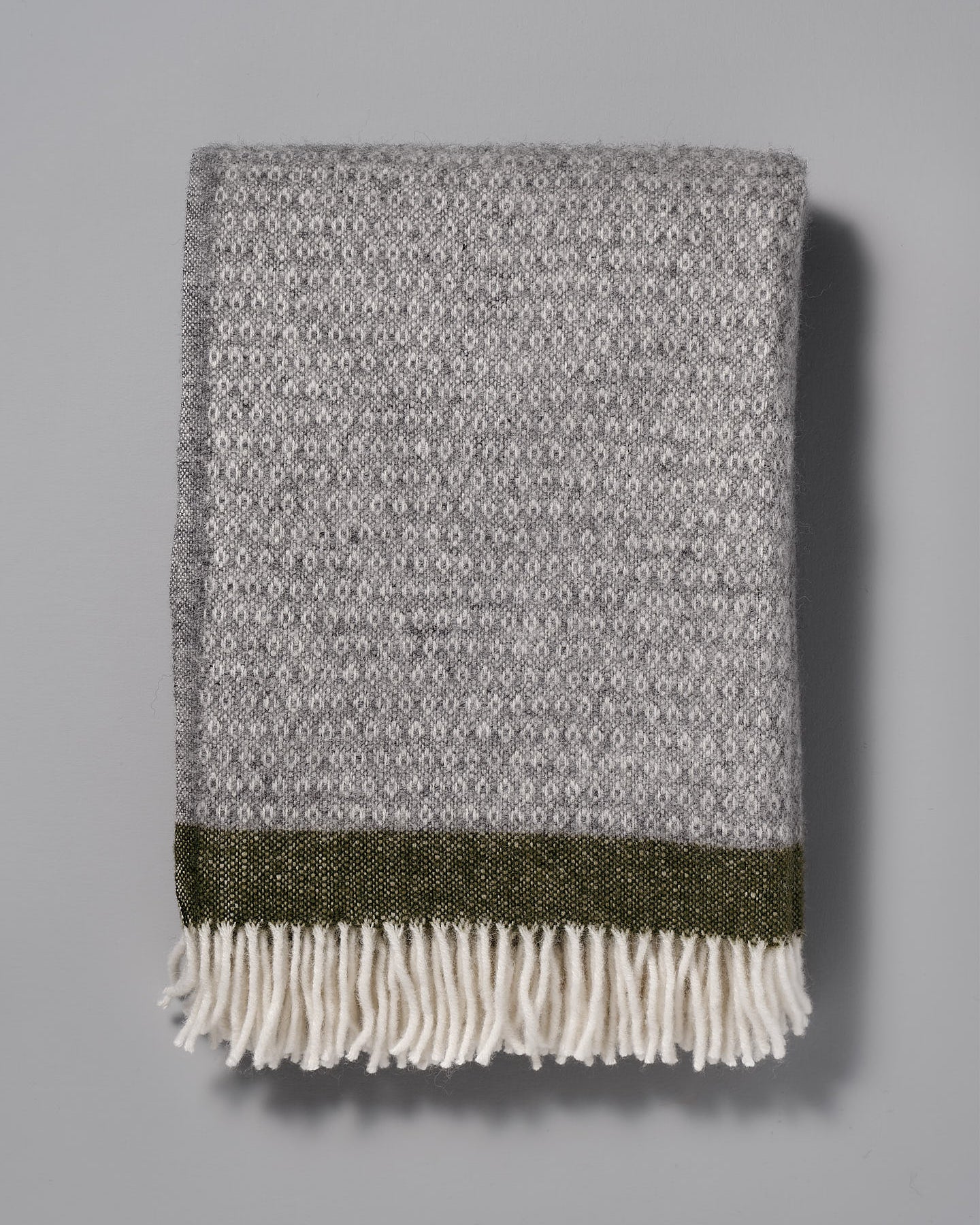 A Klippan Hampus Wool Throw - Grey Green with fringes.
