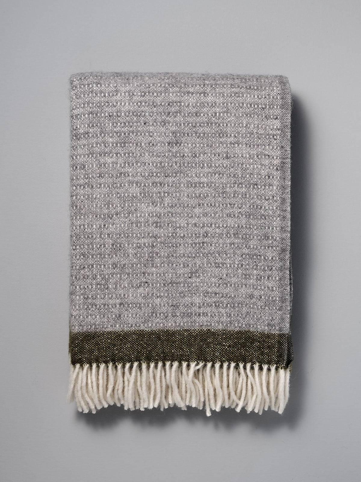 A Klippan Hampus Wool Throw - Grey Green with fringes on a white background.