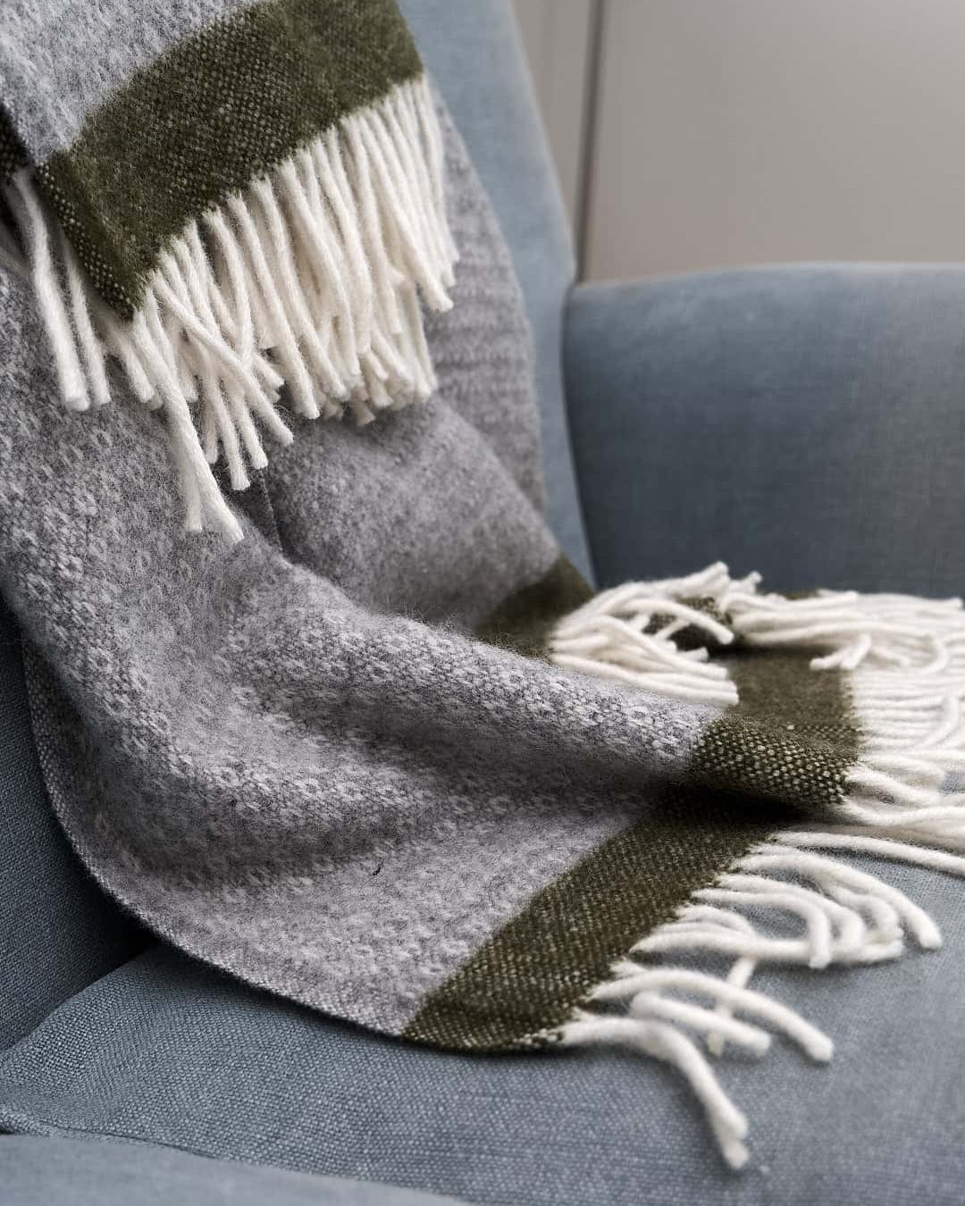 A Hampus Wool Throw - Grey Green by Klippan on a couch.