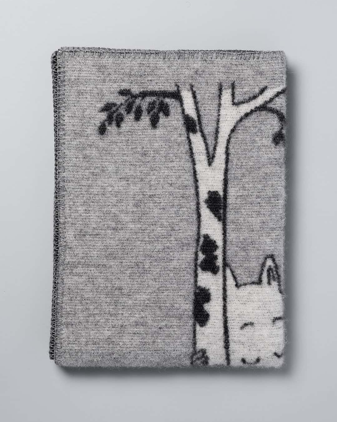 A grey Moomin Baby Blanket – Tree Hug by Klippan with an image of a cat in a tree.