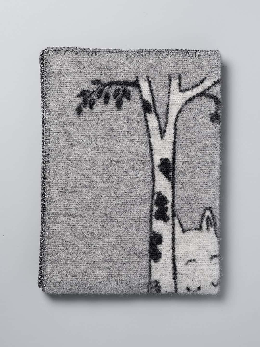 A grey Moomin Baby Blanket – Tree Hug by Klippan with an image of a cat in a tree.