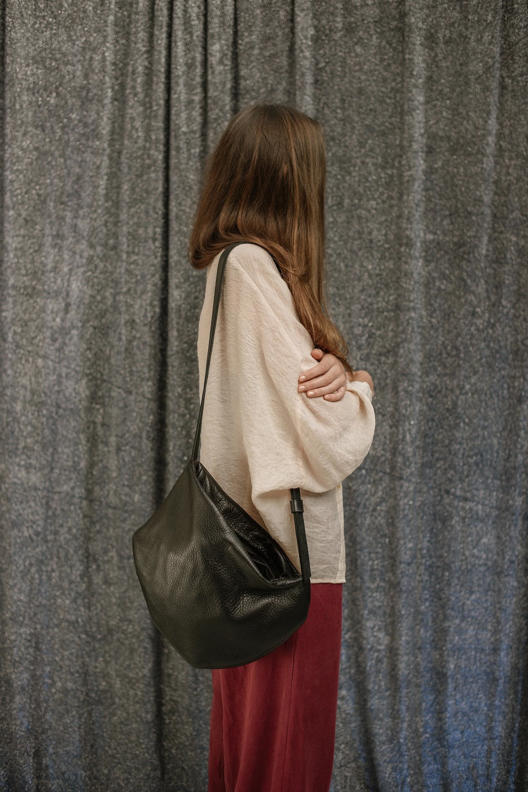 A woman holding a Side Saddle black leather shoulder bag made by Kohl &amp; Co.