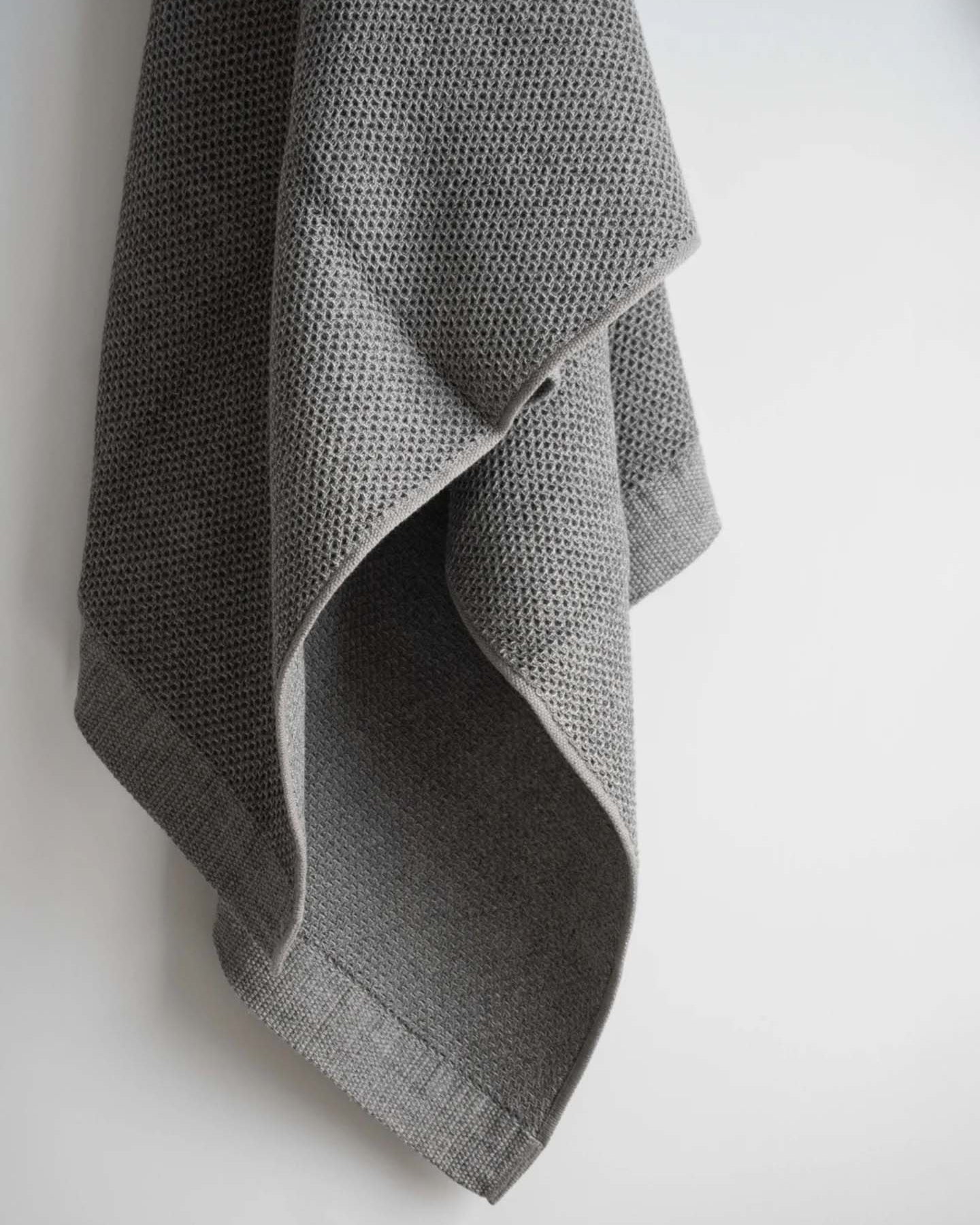 A neatly arranged set of Kontex's Vintage Waffle Towels – Bath ⋄ Hair ⋄ Hand ⋄ Face, featuring a luxurious gray waffle texture and fast-drying performance, is elegantly displayed against a plain white background.