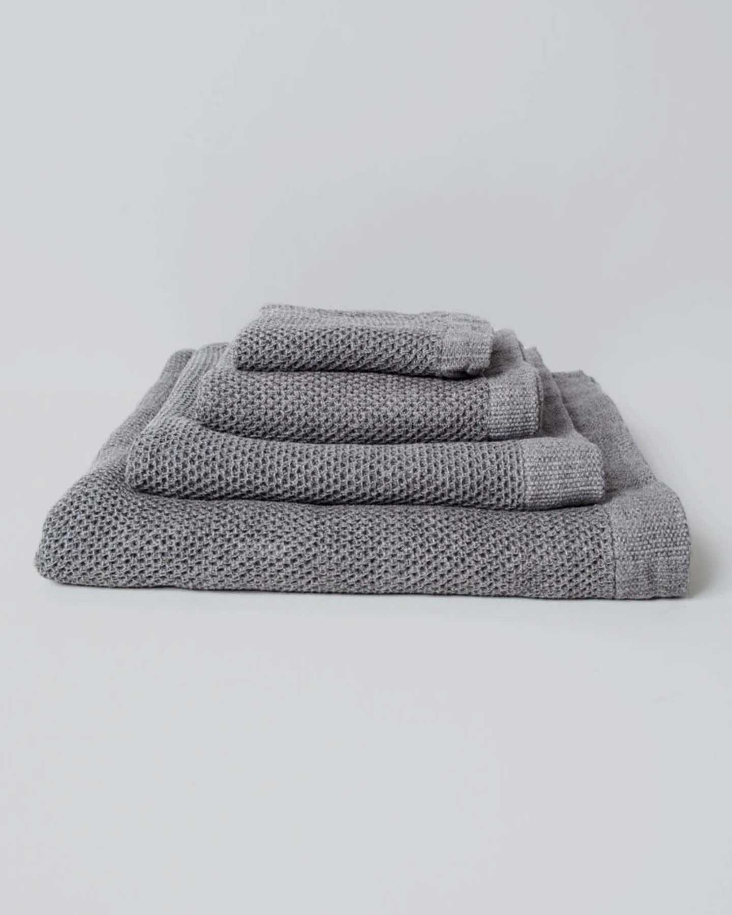 A neatly arranged set of Kontex's Vintage Waffle Towels – Bath ⋄ Hair ⋄ Hand ⋄ Face, featuring a luxurious gray waffle texture and fast-drying performance, is elegantly displayed against a plain white background.