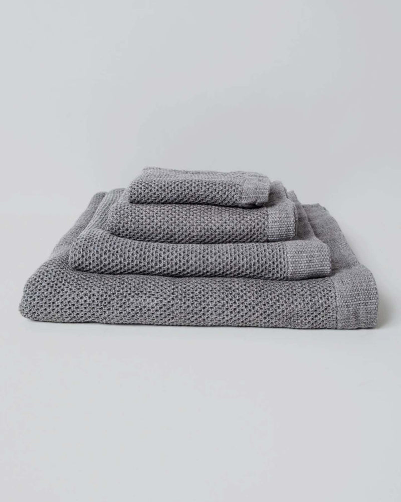 A neatly arranged set of Kontex's Vintage Waffle Towels – Bath ⋄ Hair ⋄ Hand ⋄ Face, featuring a luxurious gray waffle texture and fast-drying performance, is elegantly displayed against a plain white background.