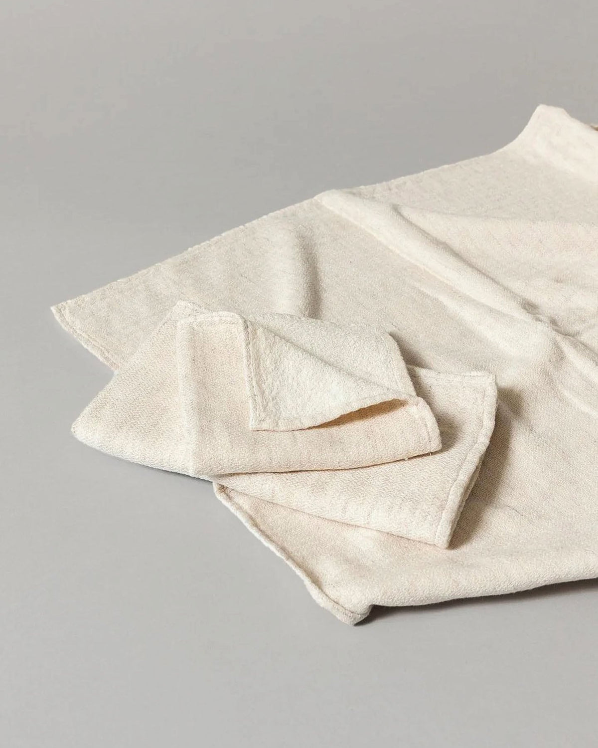 A quick-drying Claire Towel – Almond from Kontex, made of organic cotton and folded neatly, is displayed on a flat, light gray surface.