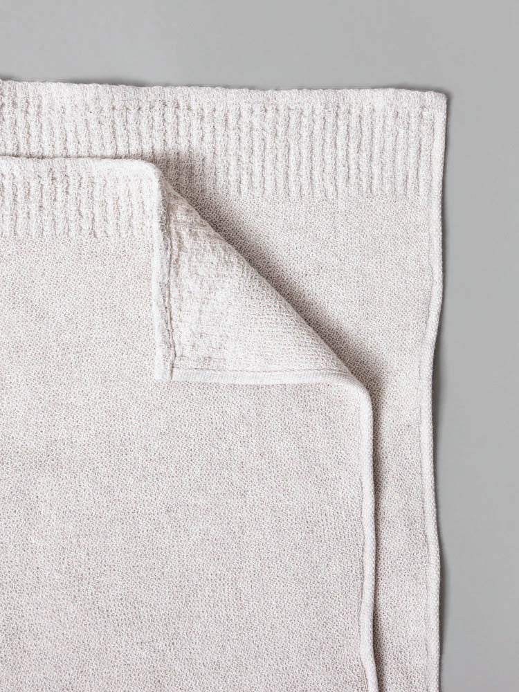 Kontex&#39;s Re.Lana Towels, crafted in beige from 100% cotton, folded on a gray surface.