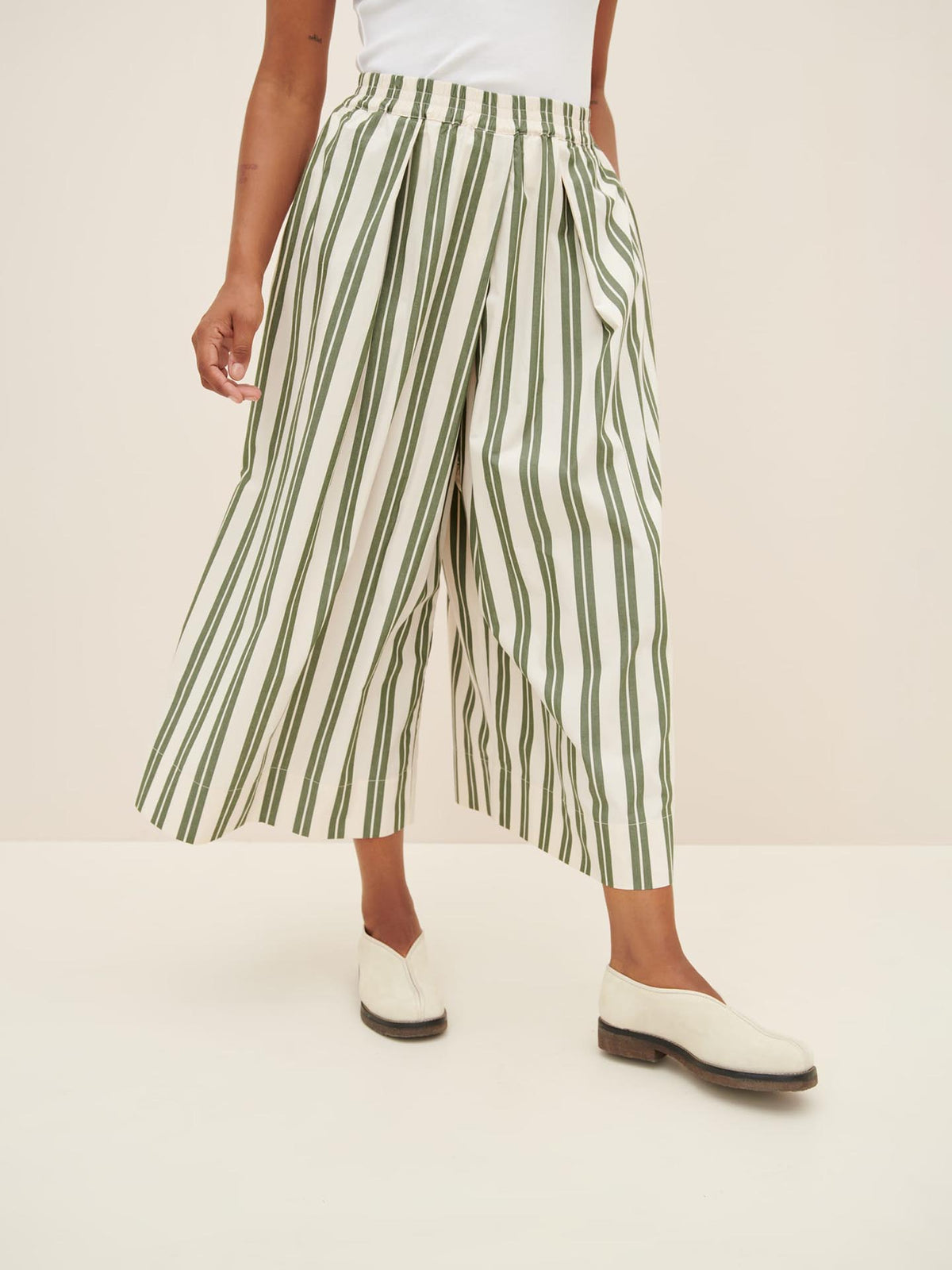 Person wearing Kowtow&#39;s Athena Pant in Forest Stripe, complemented by a white top and white shoes in a relaxed fit.