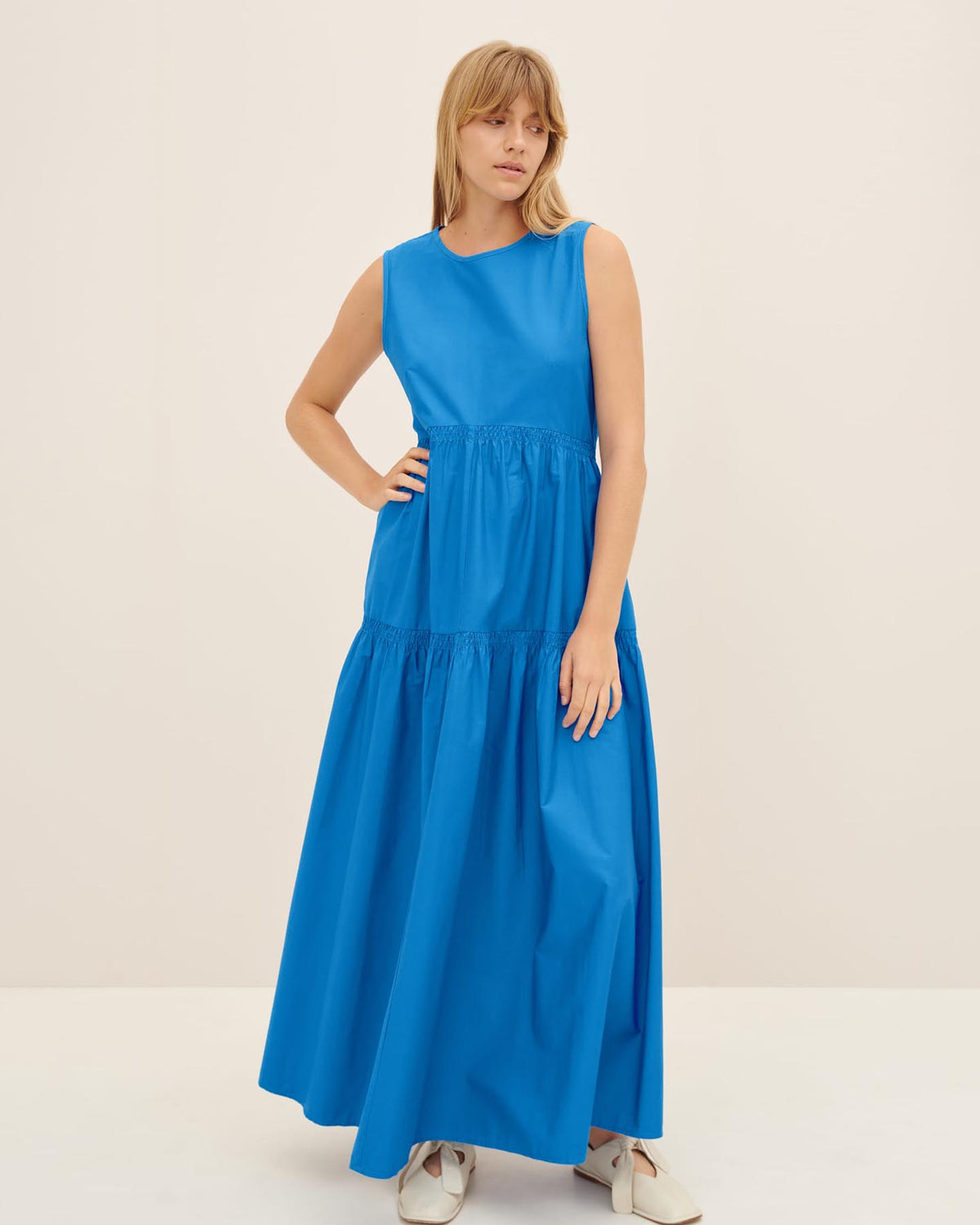 A person wearing the Aurora Dress from Kowtow in size XS stands against a plain backdrop, showcasing its standard fit.