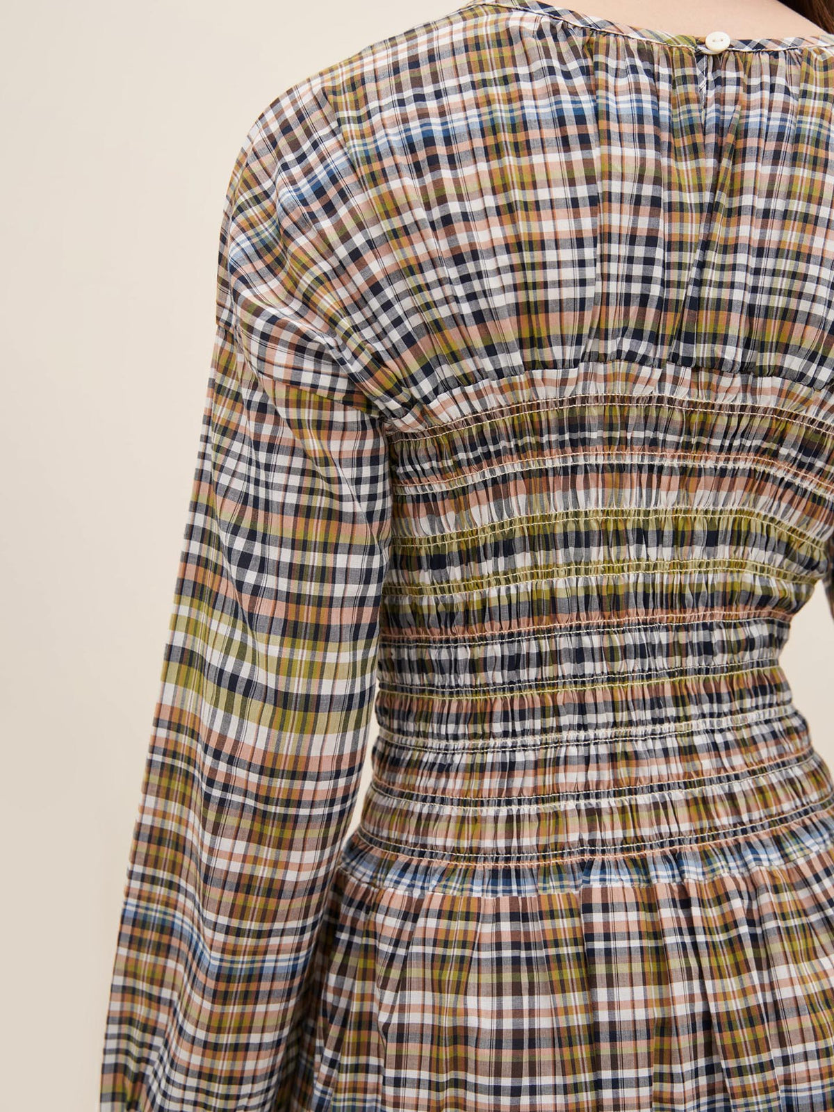 A close-up image of the back of the Kowtow Sienna Dress, a long-sleeved design featuring a multicolored plaid pattern with gathered detailing at the waist and upper back. Please refer to the product measurements for a better understanding of its standard fit.