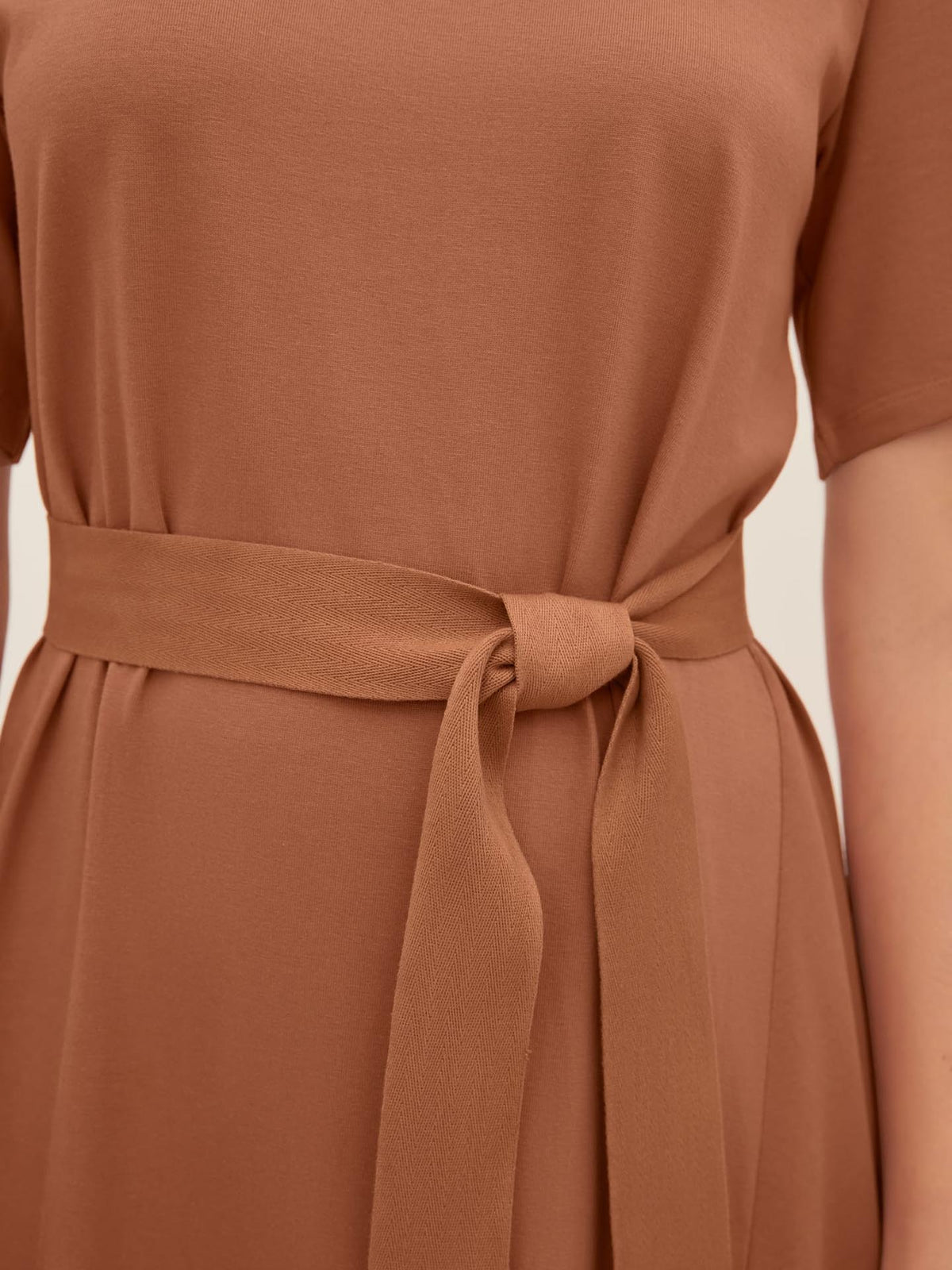 Close-up of the Kowtow T-Shirt Swing Dress in Sienna, showcasing a tied belt at the waist, smooth fabric, and short sleeves. This size XS dress features a standard fit, ensuring both style and comfort.