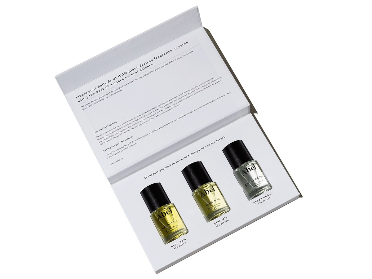Three bottles of Abel Layering Set – Cyan Nori ⋄ Green Cedar ⋄ Pink Iris natural eau de parfum presented in an open box with descriptive text on the inside of the lid.