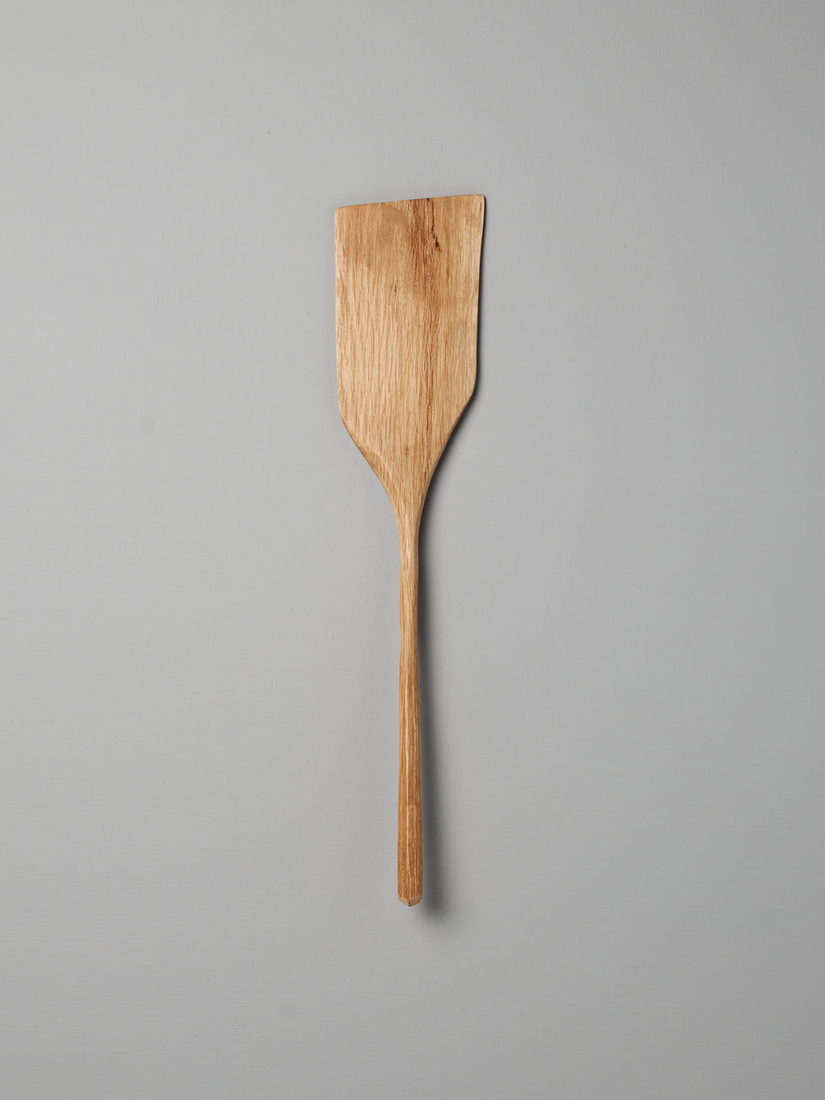 A distinct Luke Crouch wooden spatula, hand-carved from Australian She-Oak, stands against a plain grey background.