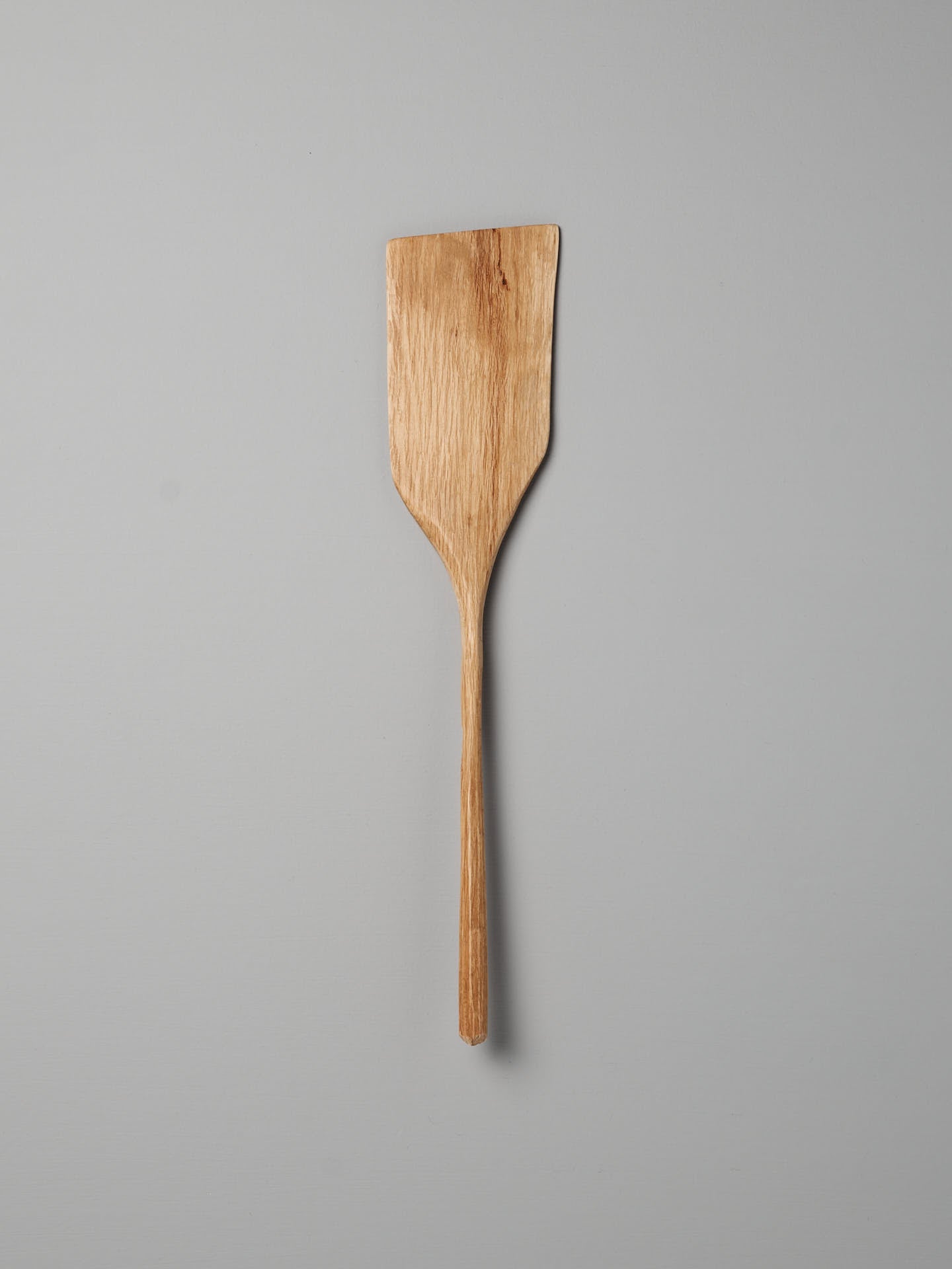 A distinct Luke Crouch wooden spatula, hand-carved from Australian She-Oak, stands against a plain grey background.