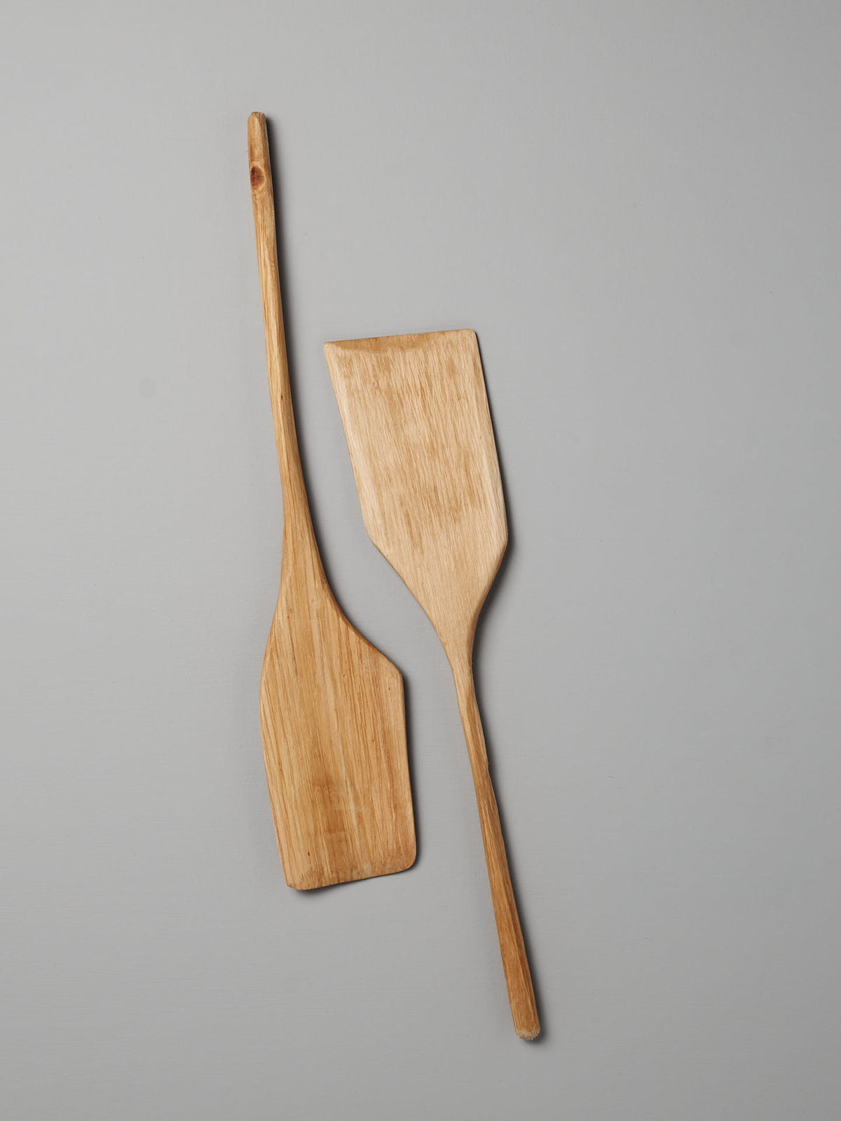 Two unique Luke Crouch Spatulas, with flat, rectangular ends and hand-carved from Australian She-Oak, are laid on a flat, light gray surface.