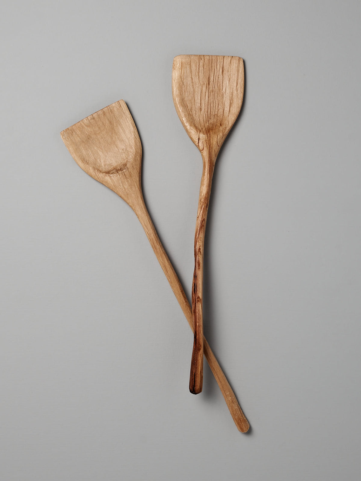 Two Wok Tools by Luke Crouch, hand-carved from Australian She-Oak, arranged in a crisscross against a gray background.