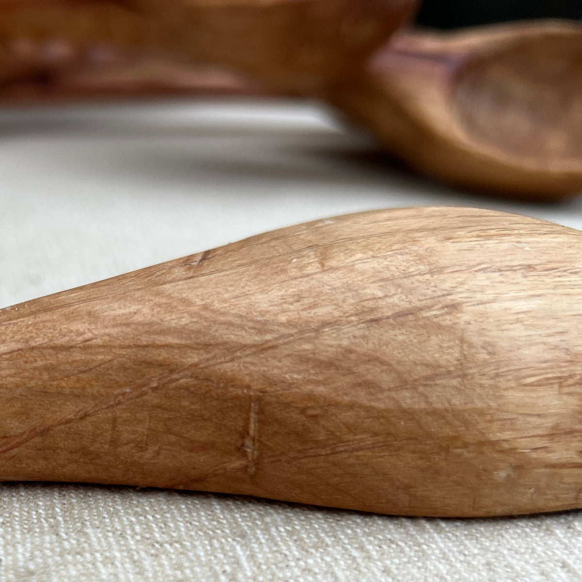 Close-up view of the Luke Crouch Straight Ladle, a hand-carved utensil made from Australian She-Oak, resting on a light-colored surface.